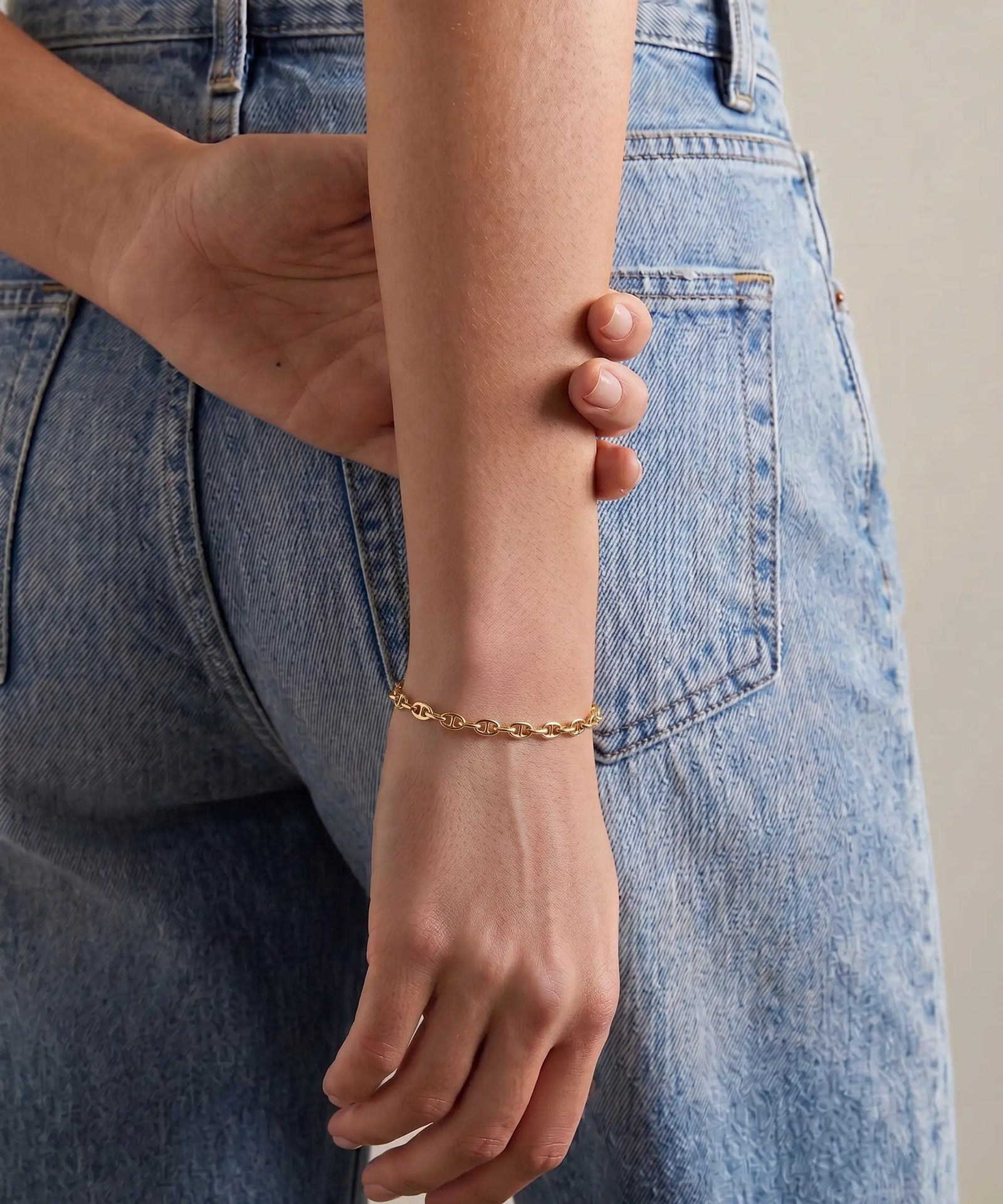 Gold bracelet on a wrist with denim jeans