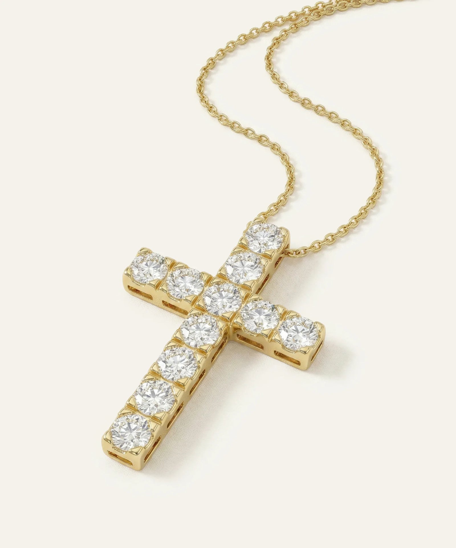 Gold cross necklace with clear gemstones on a white background