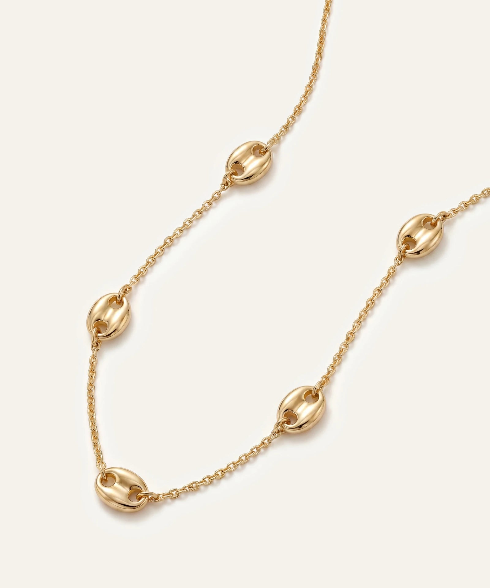 Gold chain necklace on a light beige background