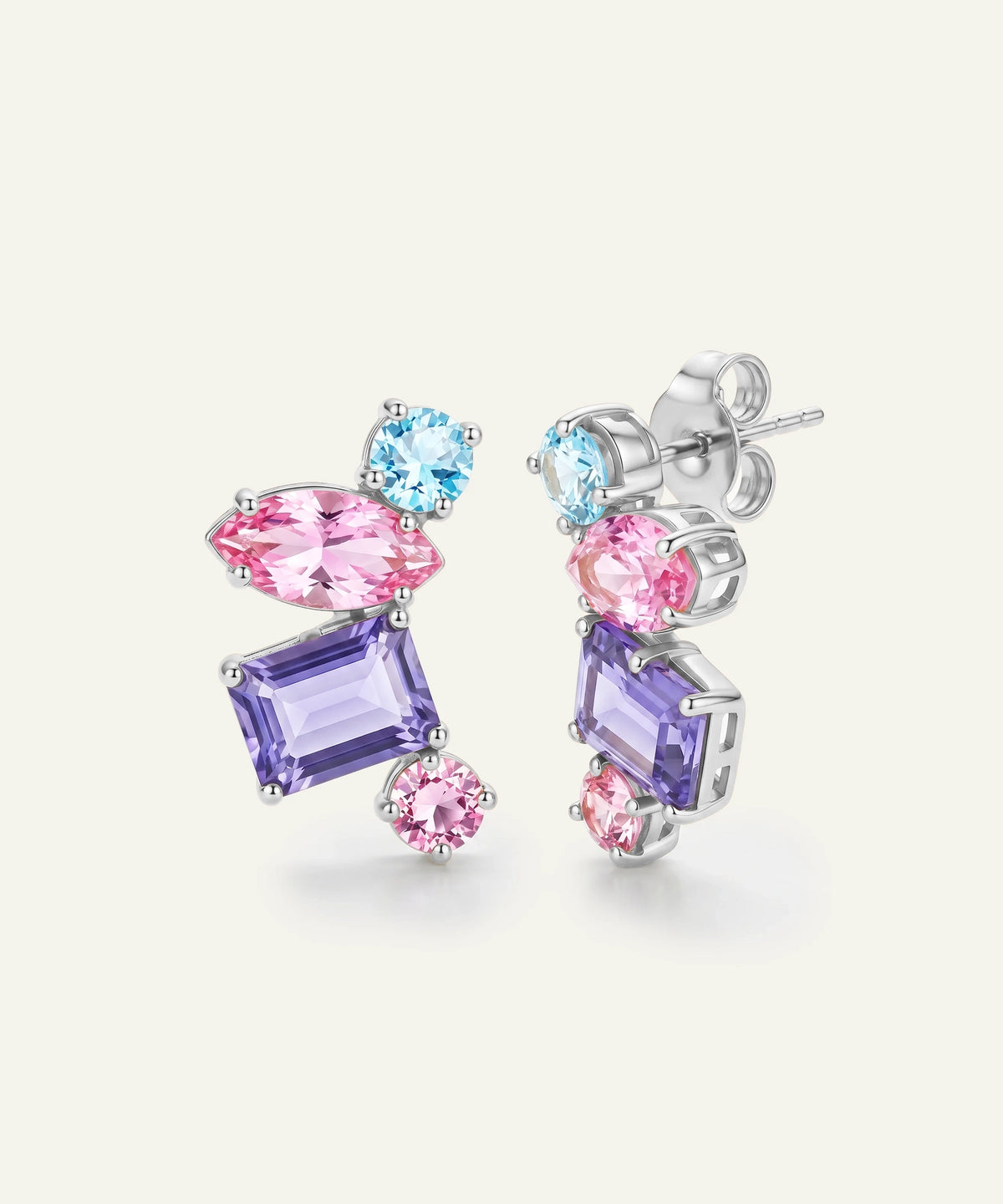 A pair of silver-toned dangle earrings featuring a vertical arrangement of light blue, marquise pink, and rectangular purple gemstones accented with small round pink stones, set against a plain off-white background.