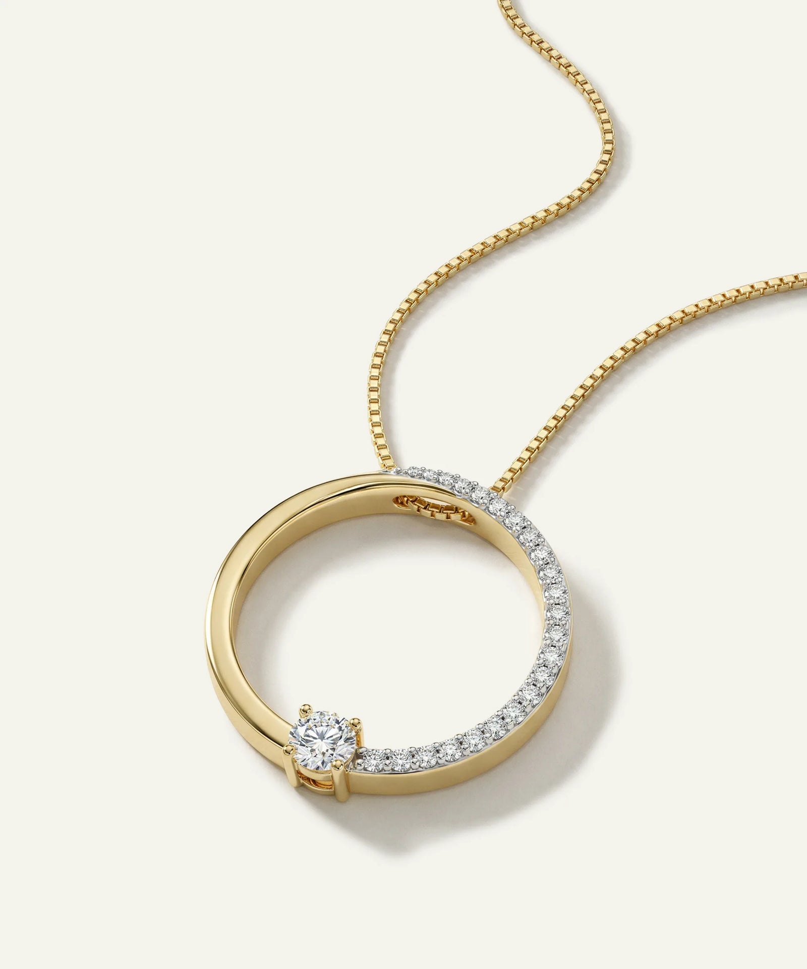 Gold necklace with a circular pendant on a light background