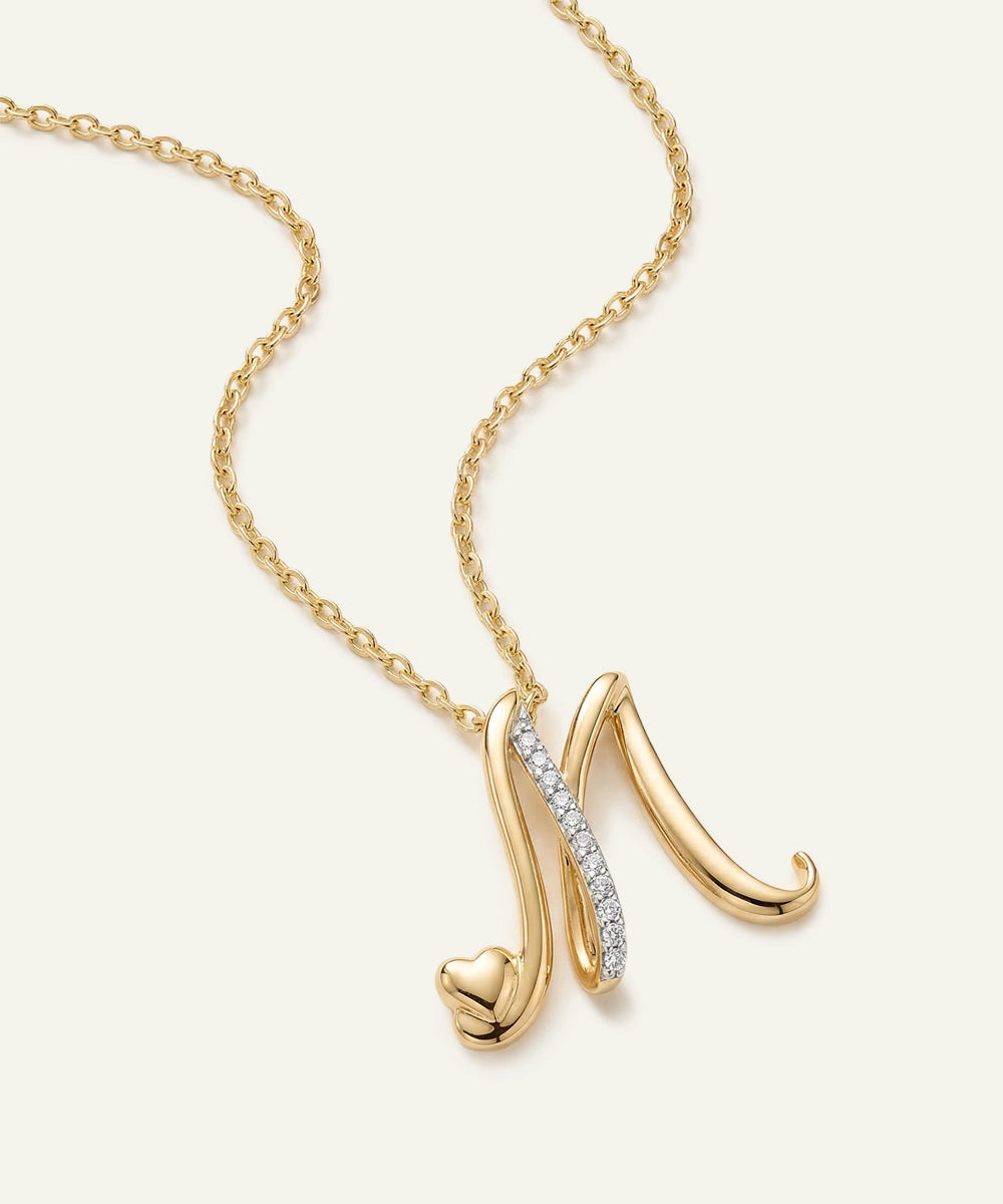 Gold necklace with a heart-shaped pendant on a light beige background