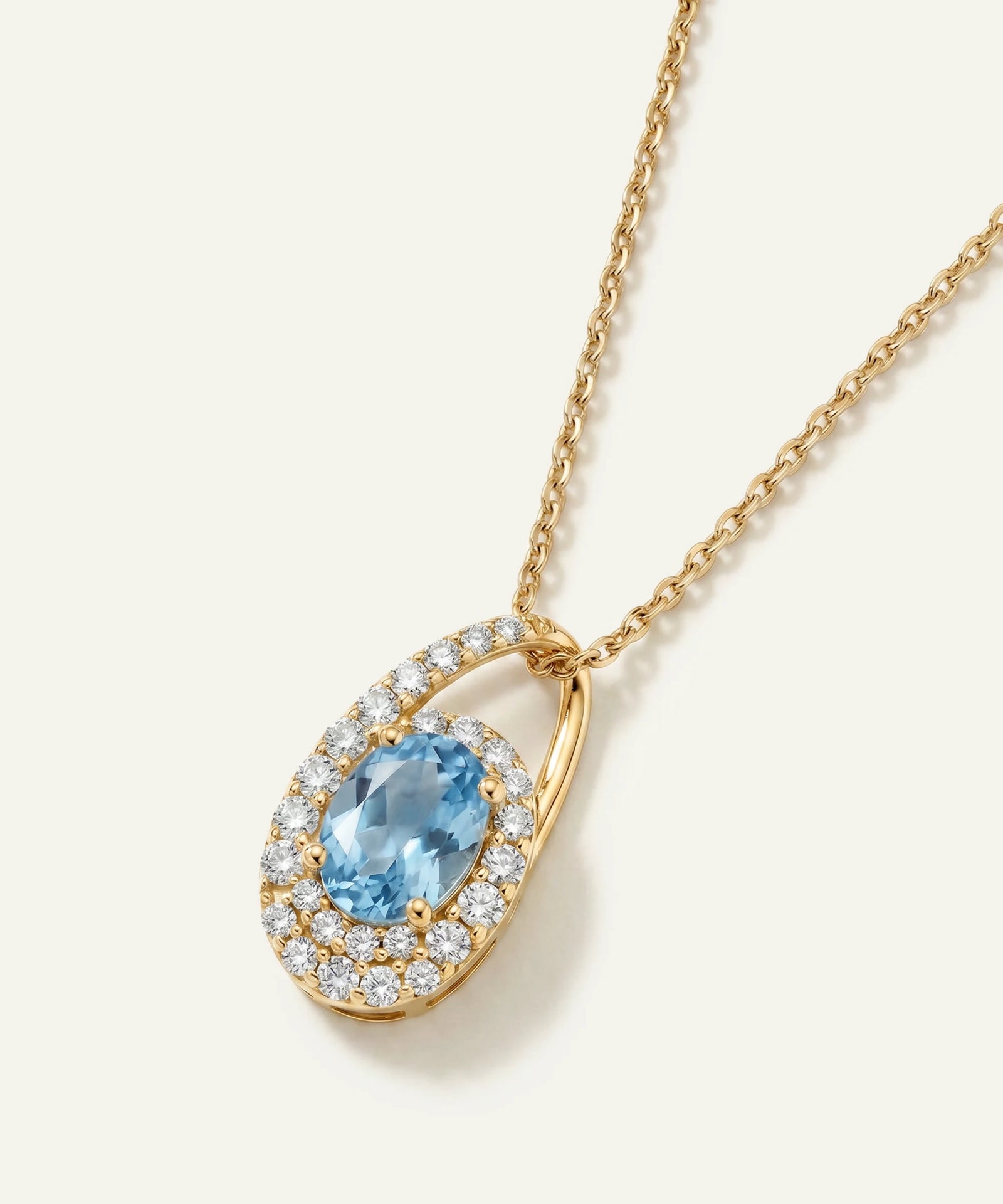 Gold necklace with a blue gemstone pendant on a white background