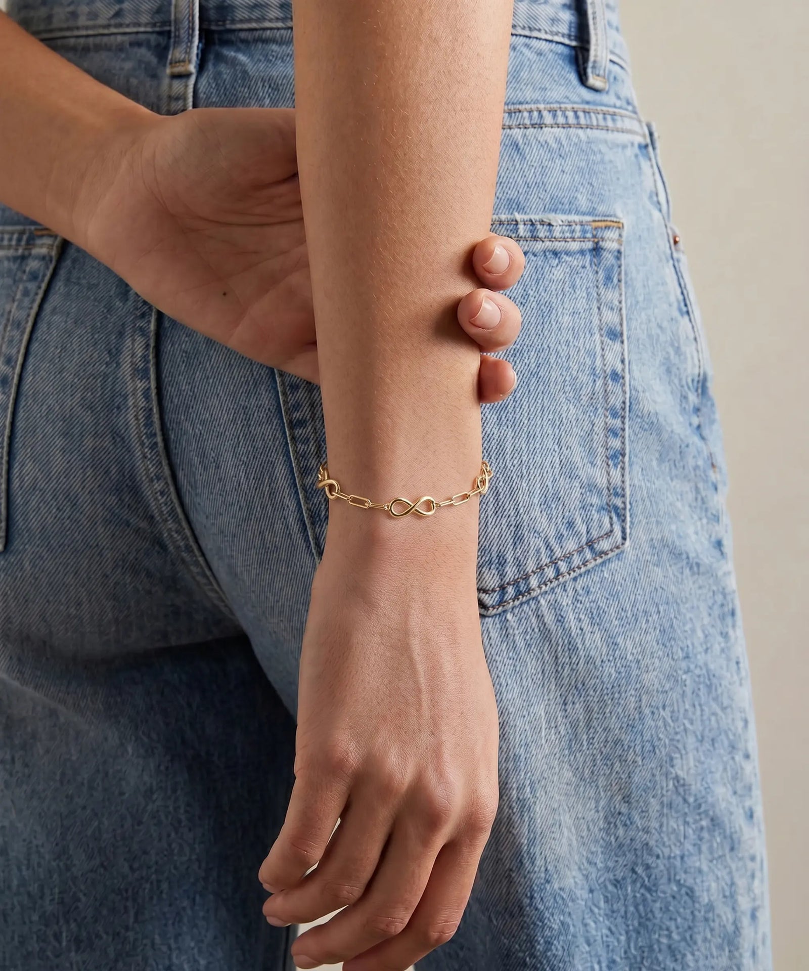 Gold bracelet on a person's wrist with denim jeans