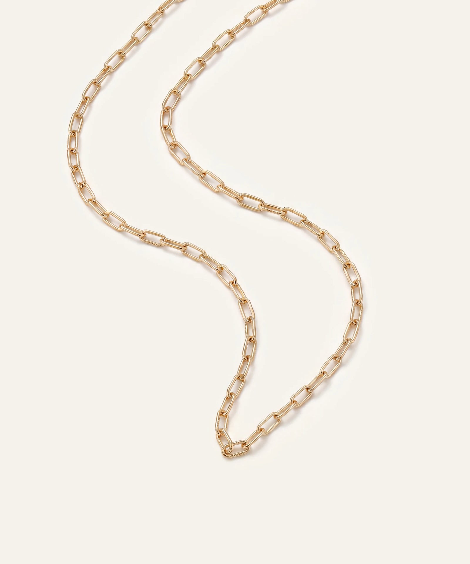 Gold chain necklace on a light beige background