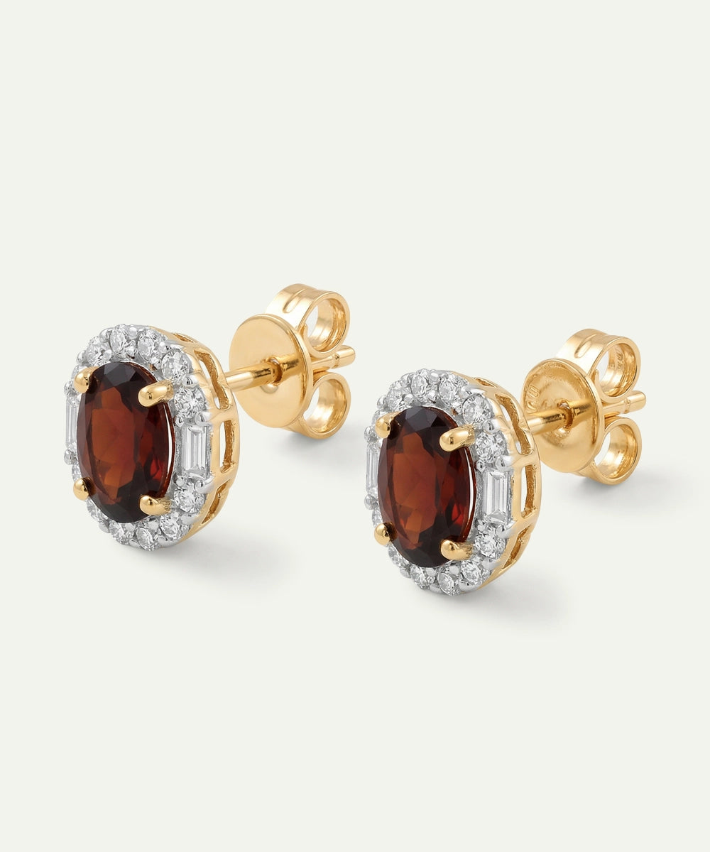 Gold earrings with red gemstones on a white background