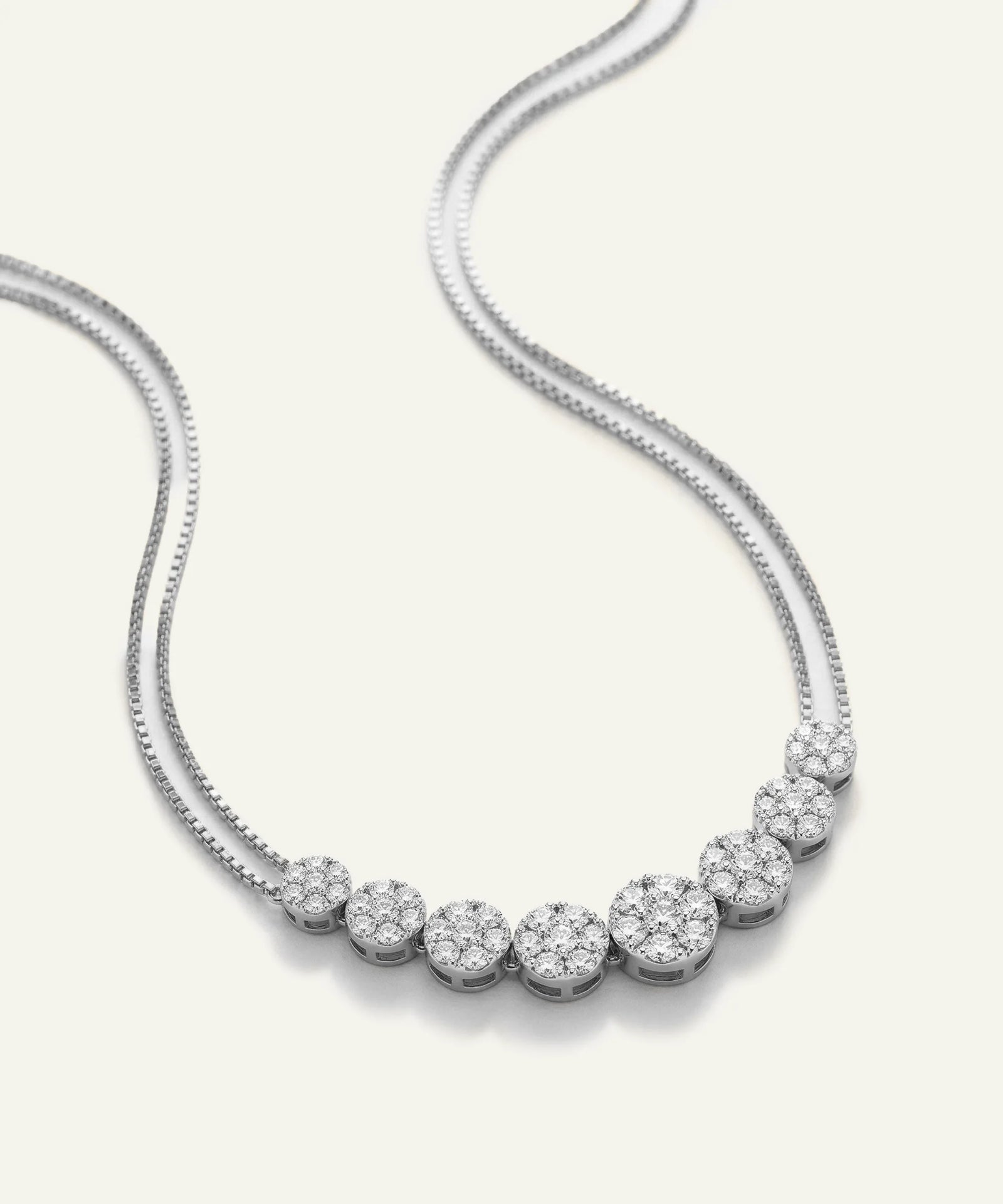 Silver necklace with round diamonds on a white background