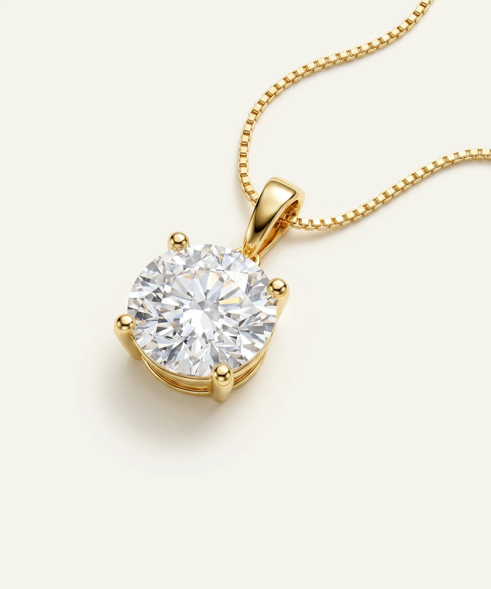 Gold necklace with a round diamond pendant on a light beige background