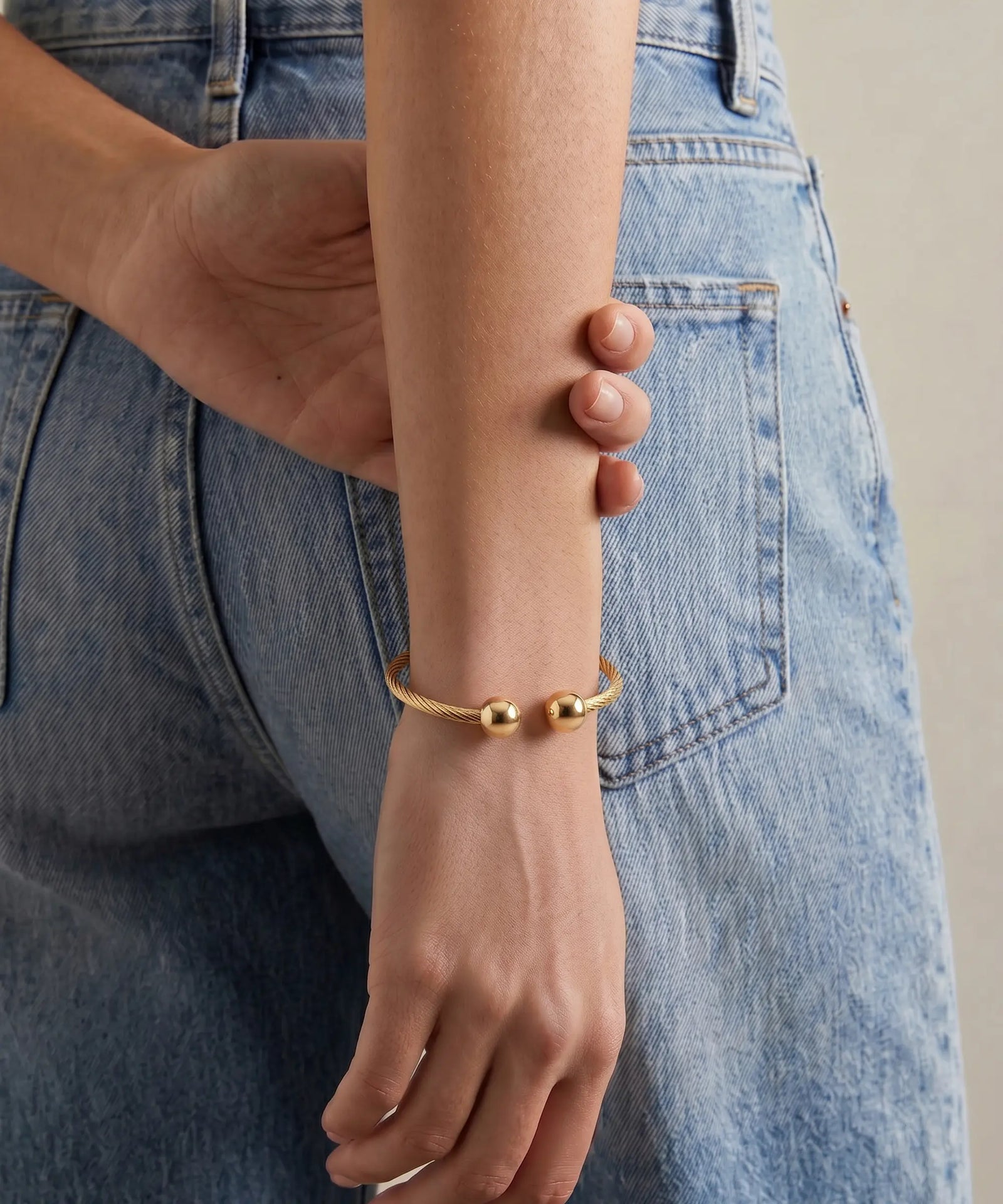 Gold bracelet on a wrist with denim jeans