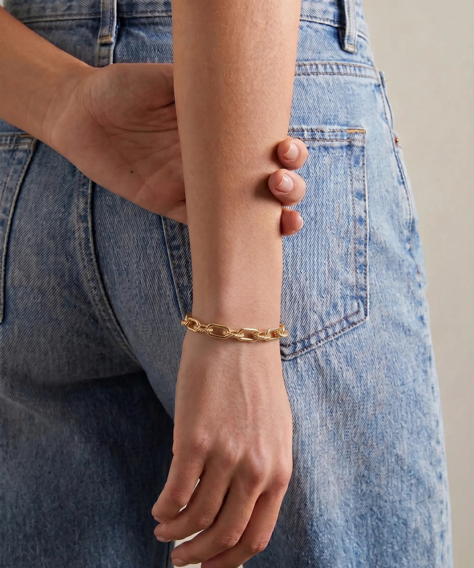 Gold bracelet on a wrist with denim jeans