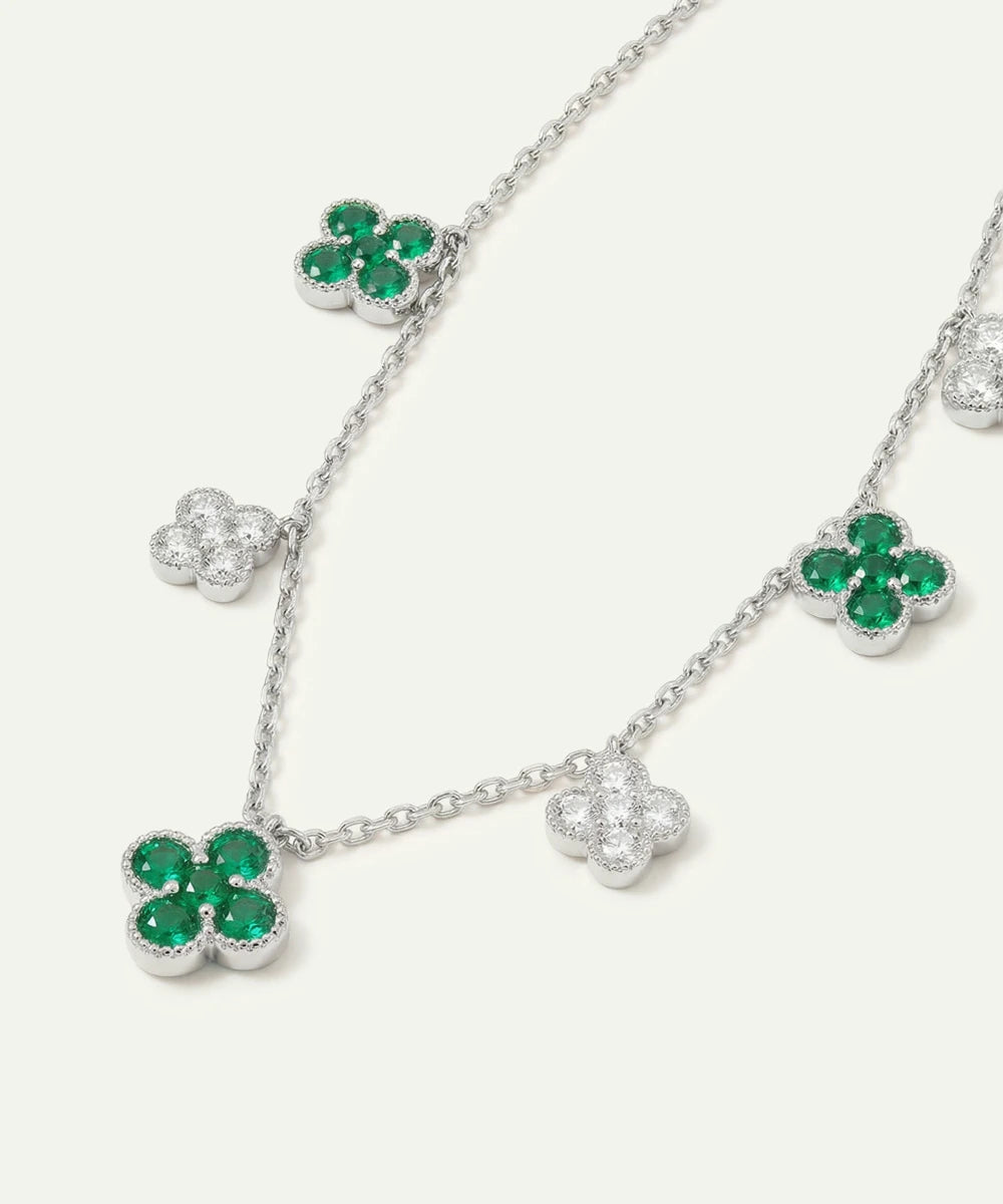 Silver necklace with green gemstone clover pendants on a white background