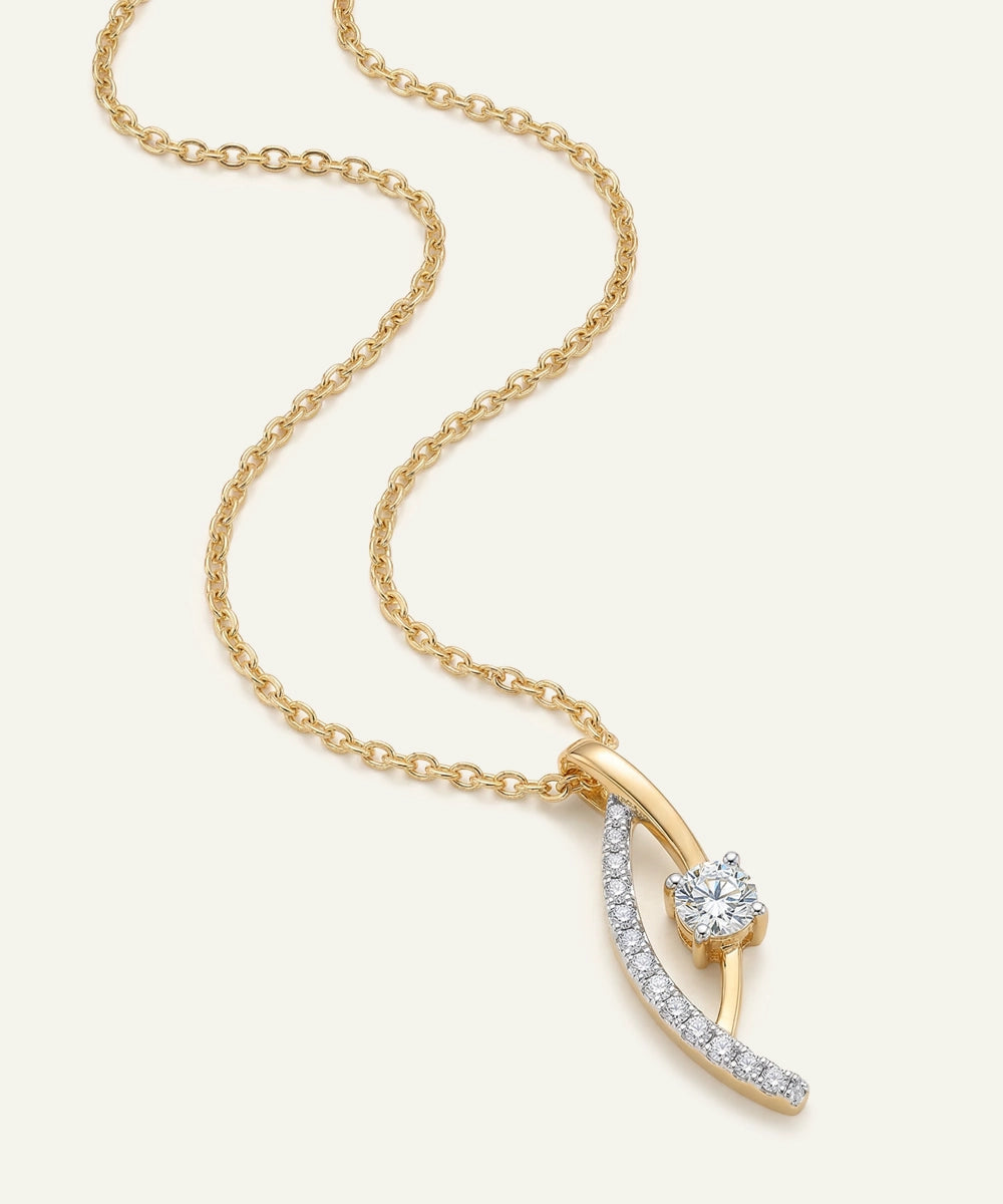 Gold necklace with a diamond pendant on a light beige background