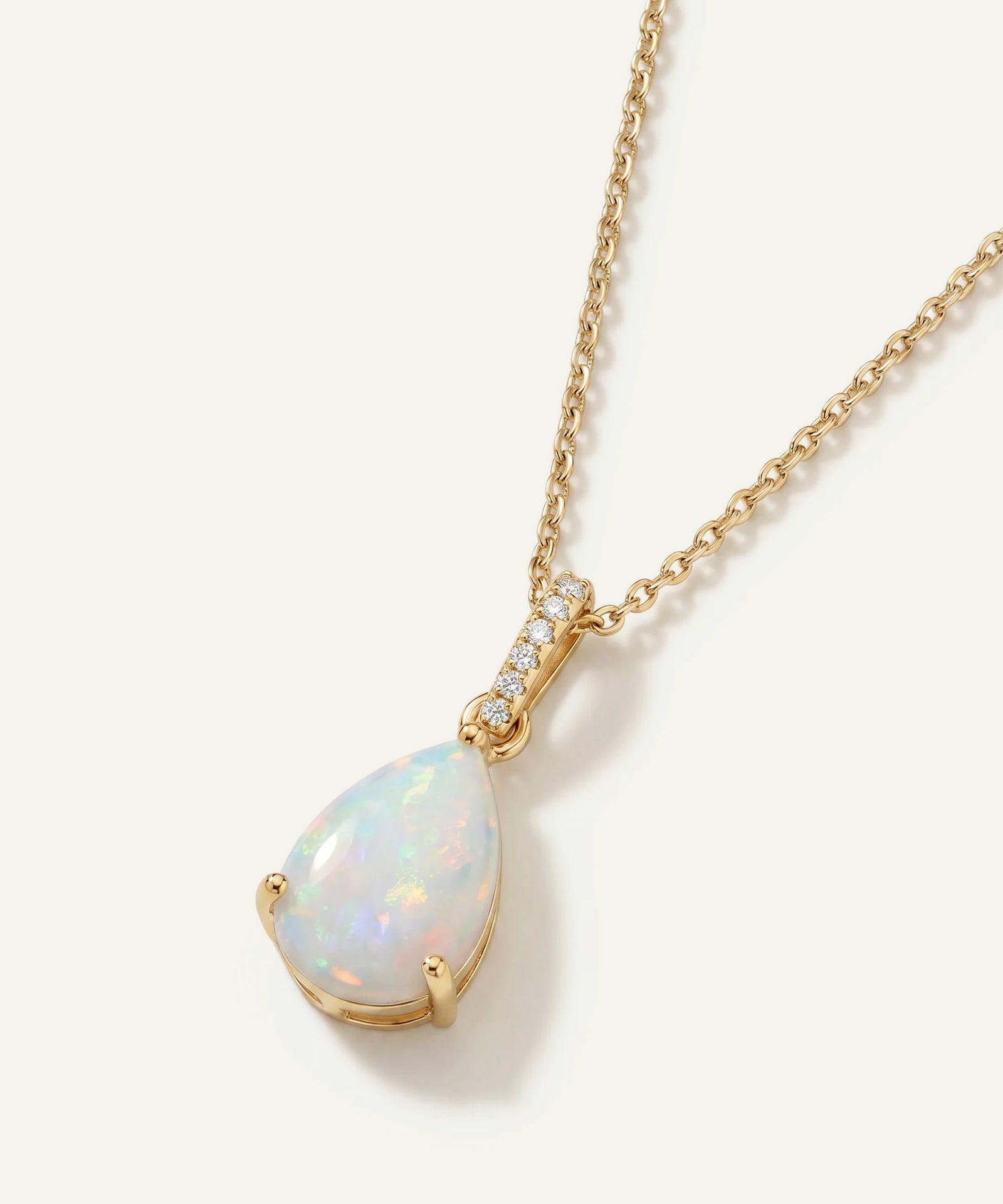 Gold necklace with a teardrop-shaped opal pendant on a white background