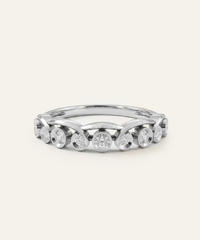 A silver-toned diamond band ring featuring a series of round clear diamonds housed in distinct, arching bezel settings, centered against a solid off-white background. - alternate view