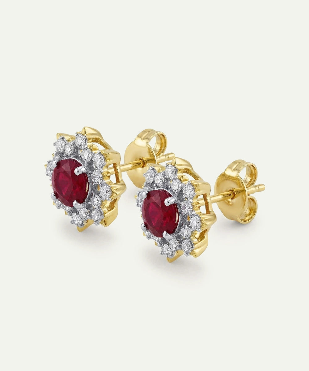 Gold earrings with red gemstones and diamond-like stones on a white background