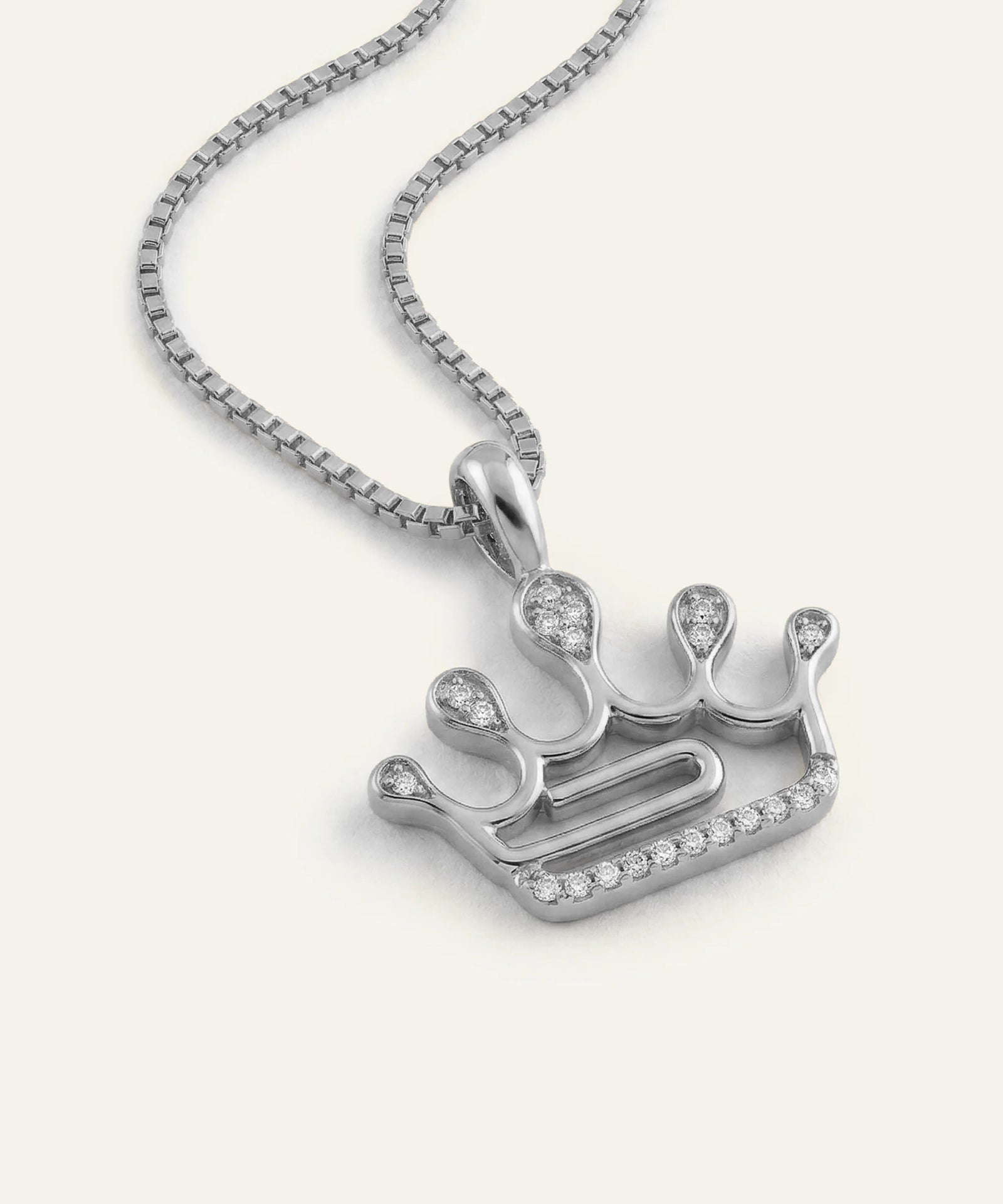 Silver crown-shaped pendant with small stones on a white background
