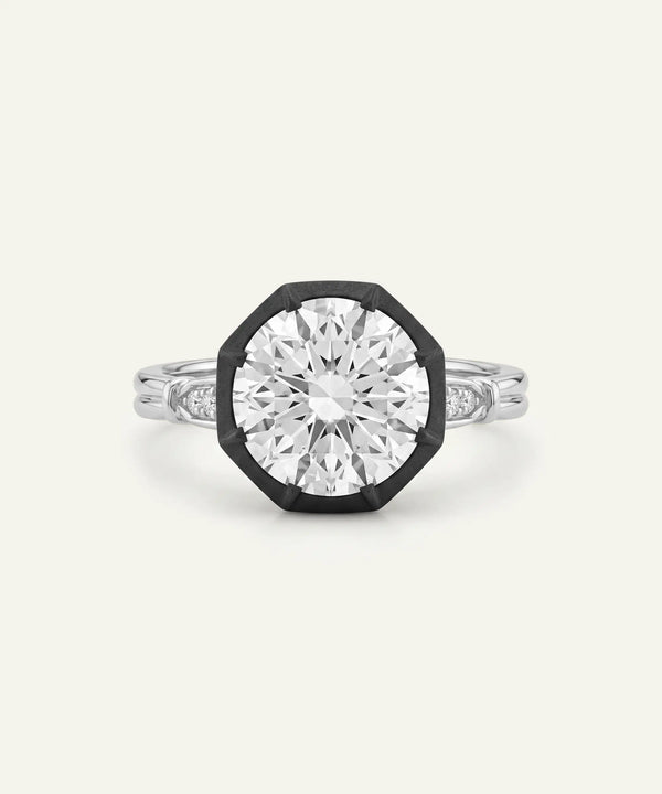 A silver-toned octagonal ring with a large clear round-cut center stone and smaller side stones, shown on a plain light background.