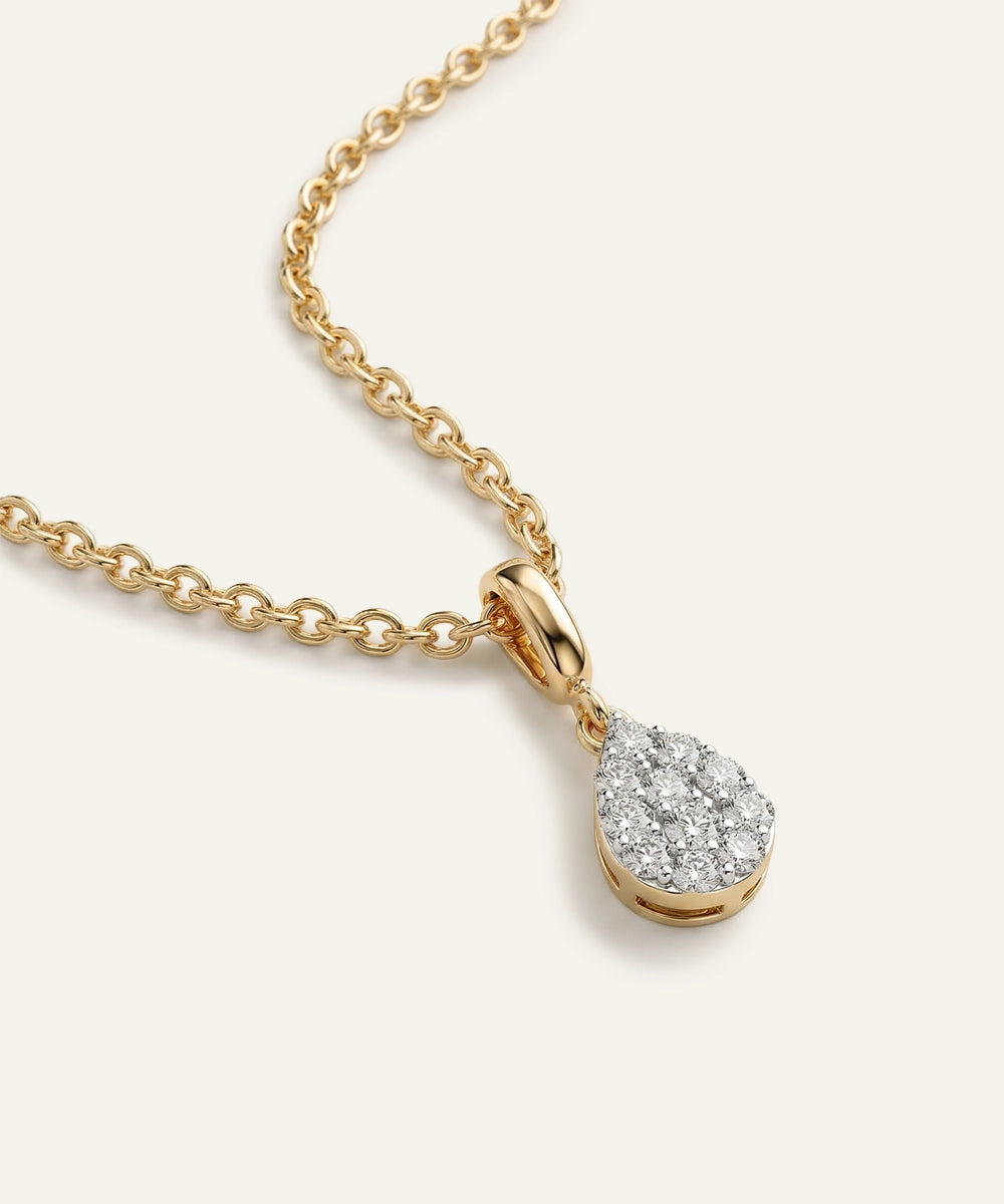 Gold necklace with a teardrop-shaped diamond pendant on a white background