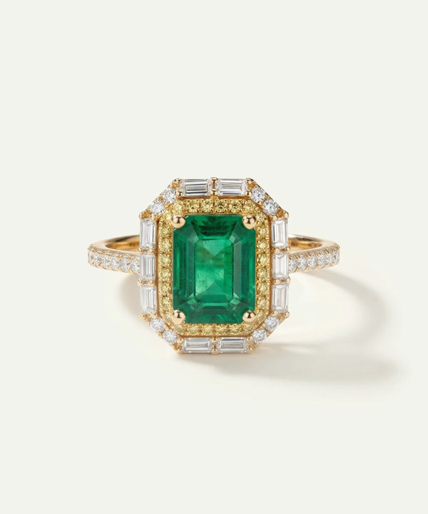 Gold ring with a green gemstone and diamond accents on a white background