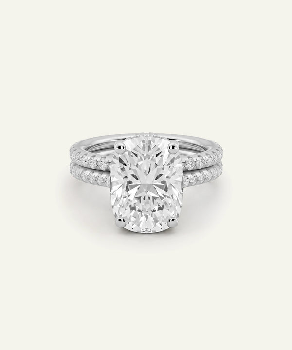 An oval-cut diamond engagement ring with a matching pavé band, shown on a clean off-white background.
