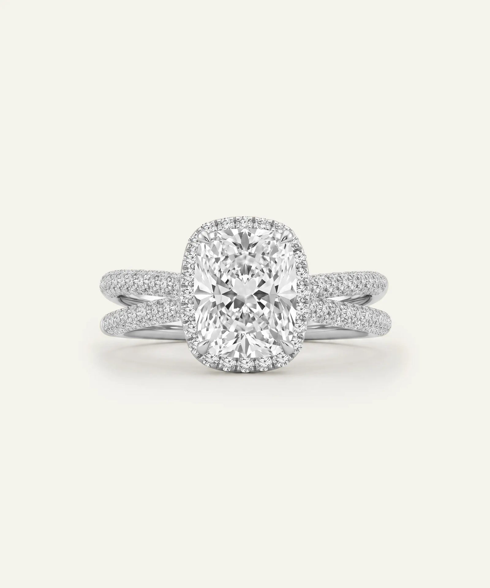 A radiant cut diamond engagement ring with a halo setting and a matching shank, both pavé-set with small diamonds, shown on a light cream background.