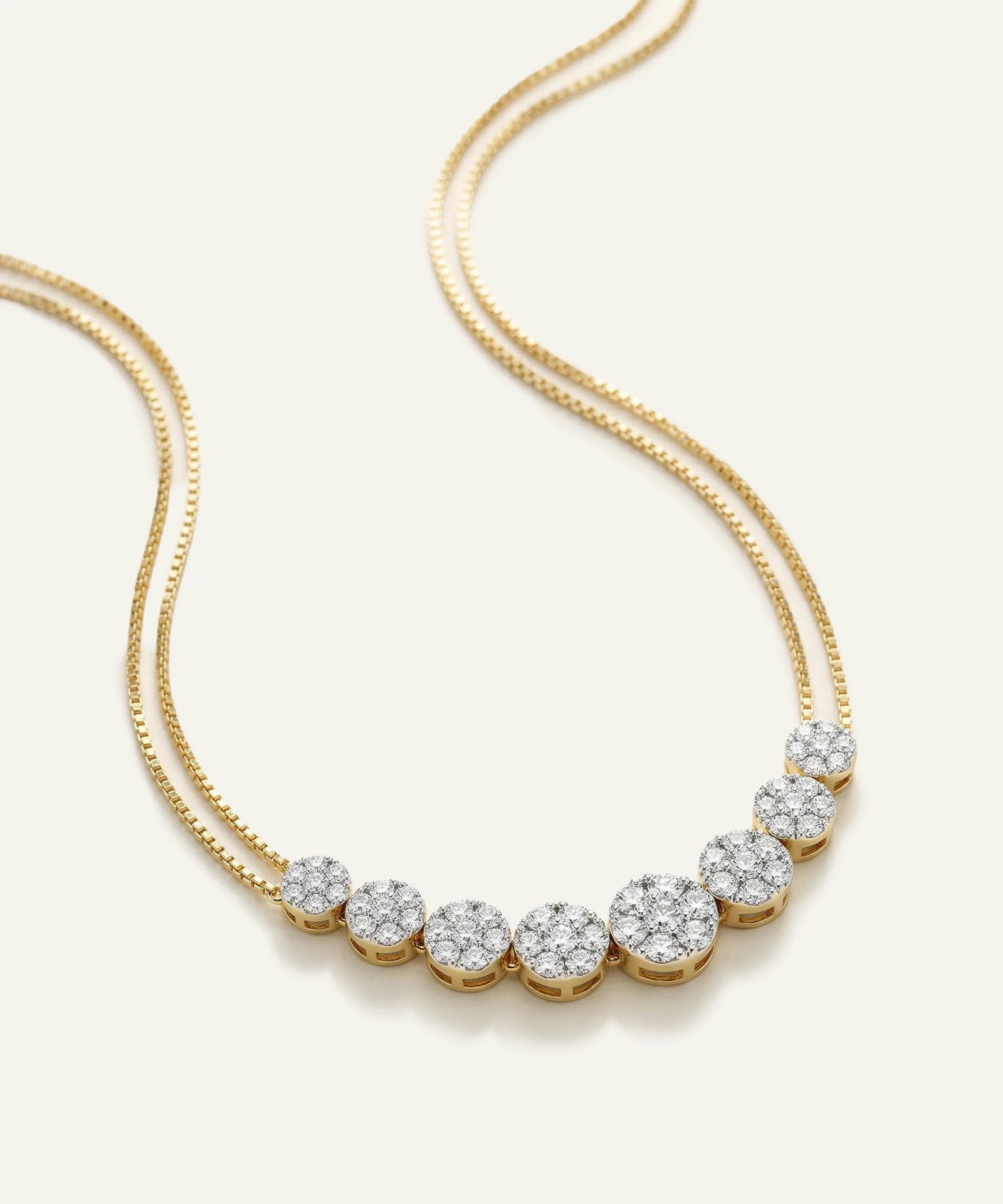 Gold necklace with diamond beads on a light beige background