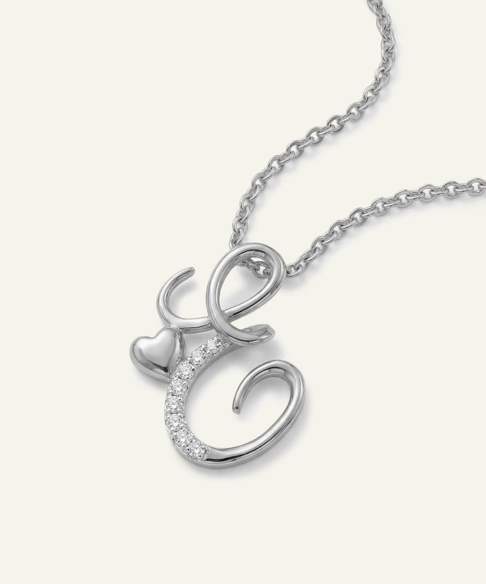 Silver necklace with a heart and 'C' pendant on a white background