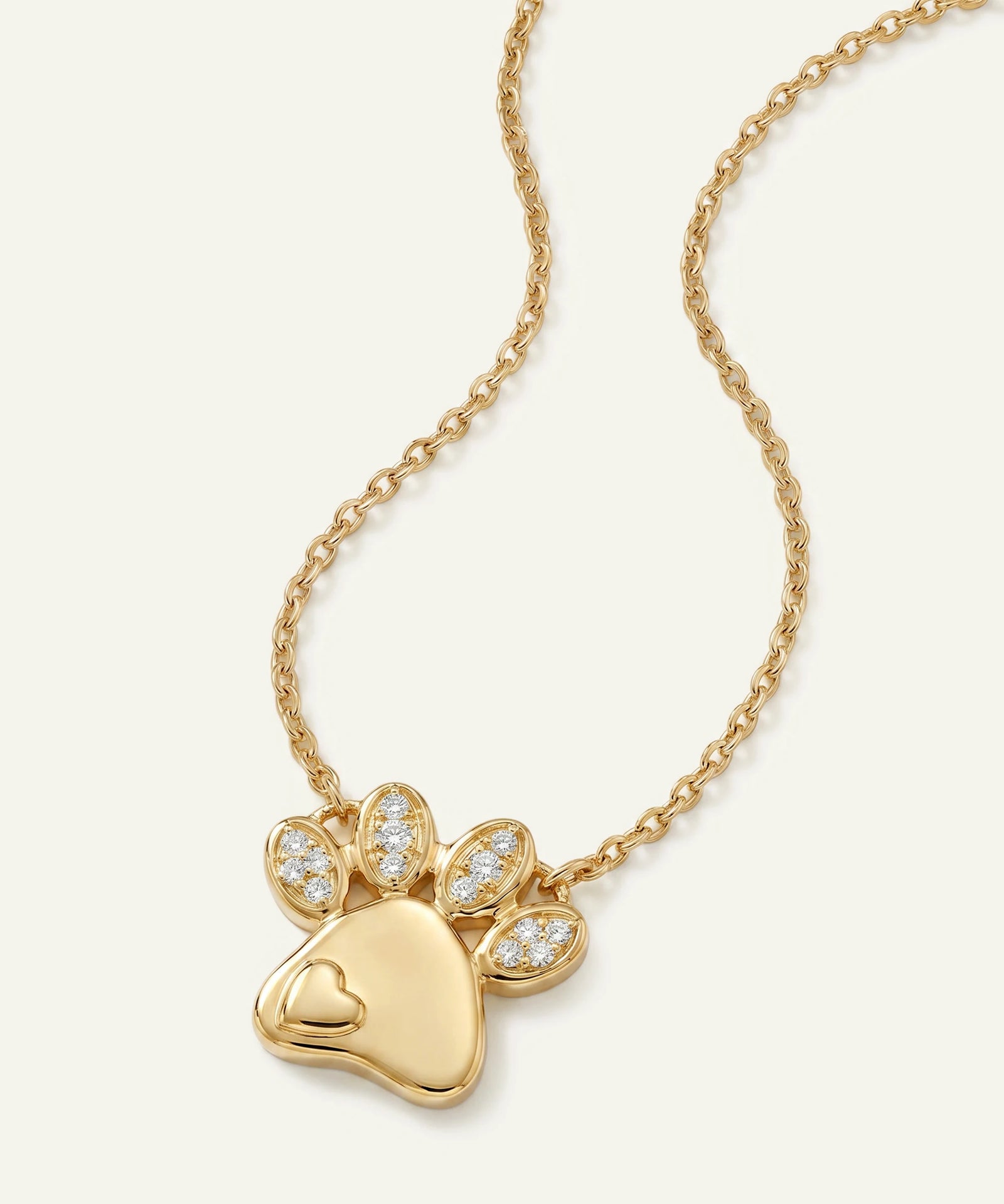 Gold necklace with a paw-shaped pendant on a white background