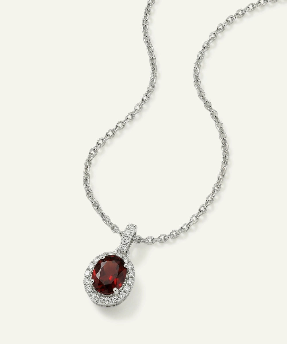 Silver necklace with a red gemstone pendant on a white background