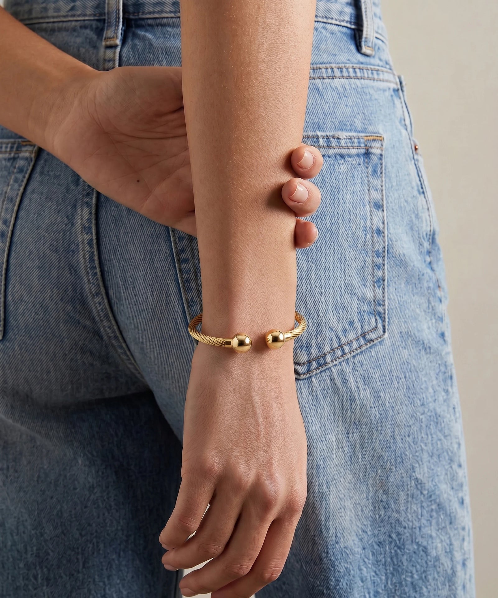 Gold bracelet on a wrist with denim jeans