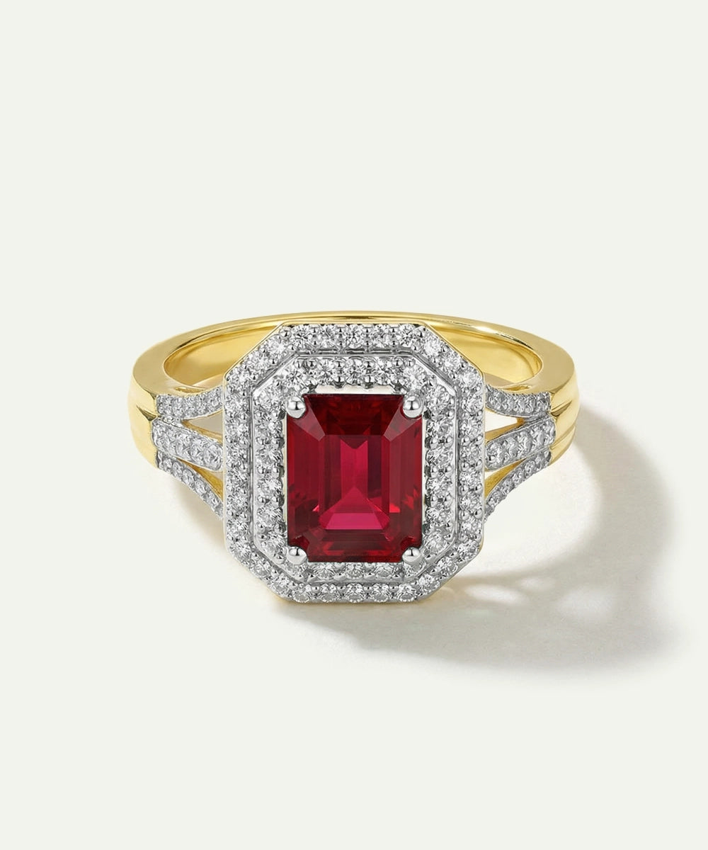 Gold ring with a red gemstone and diamond accents on a white background