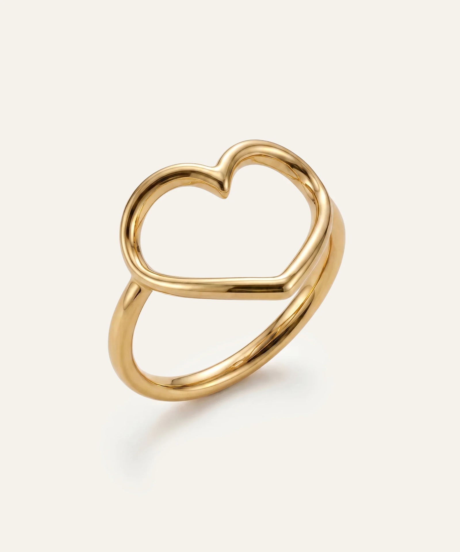 Gold heart-shaped ring on a light beige background