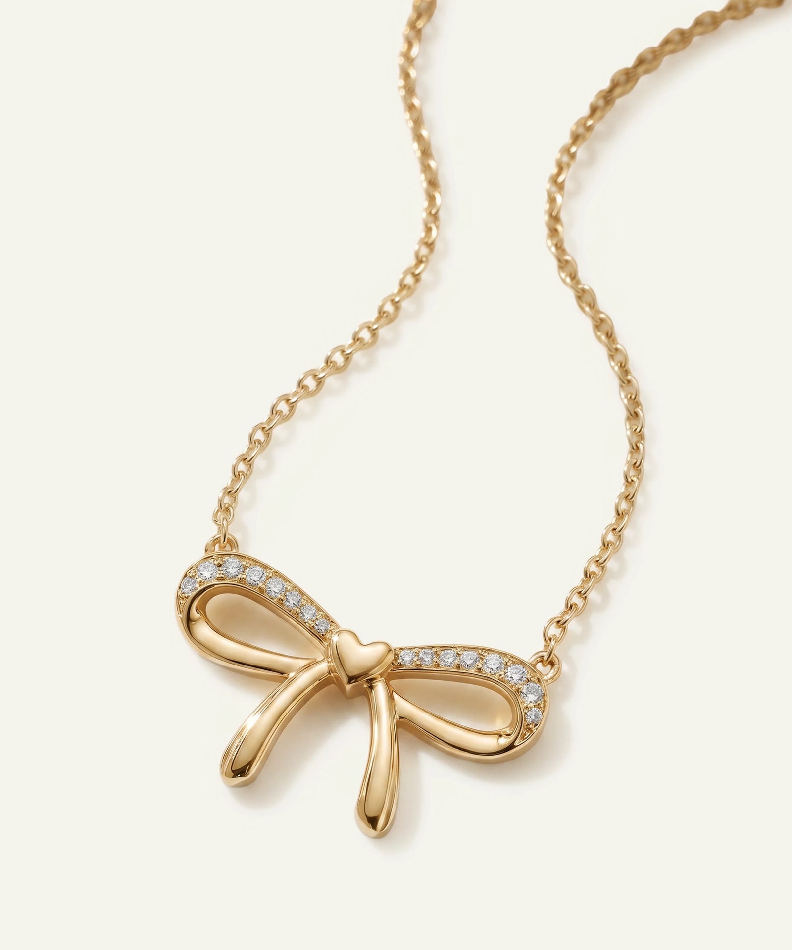 Gold bow-shaped necklace with diamonds on a white background