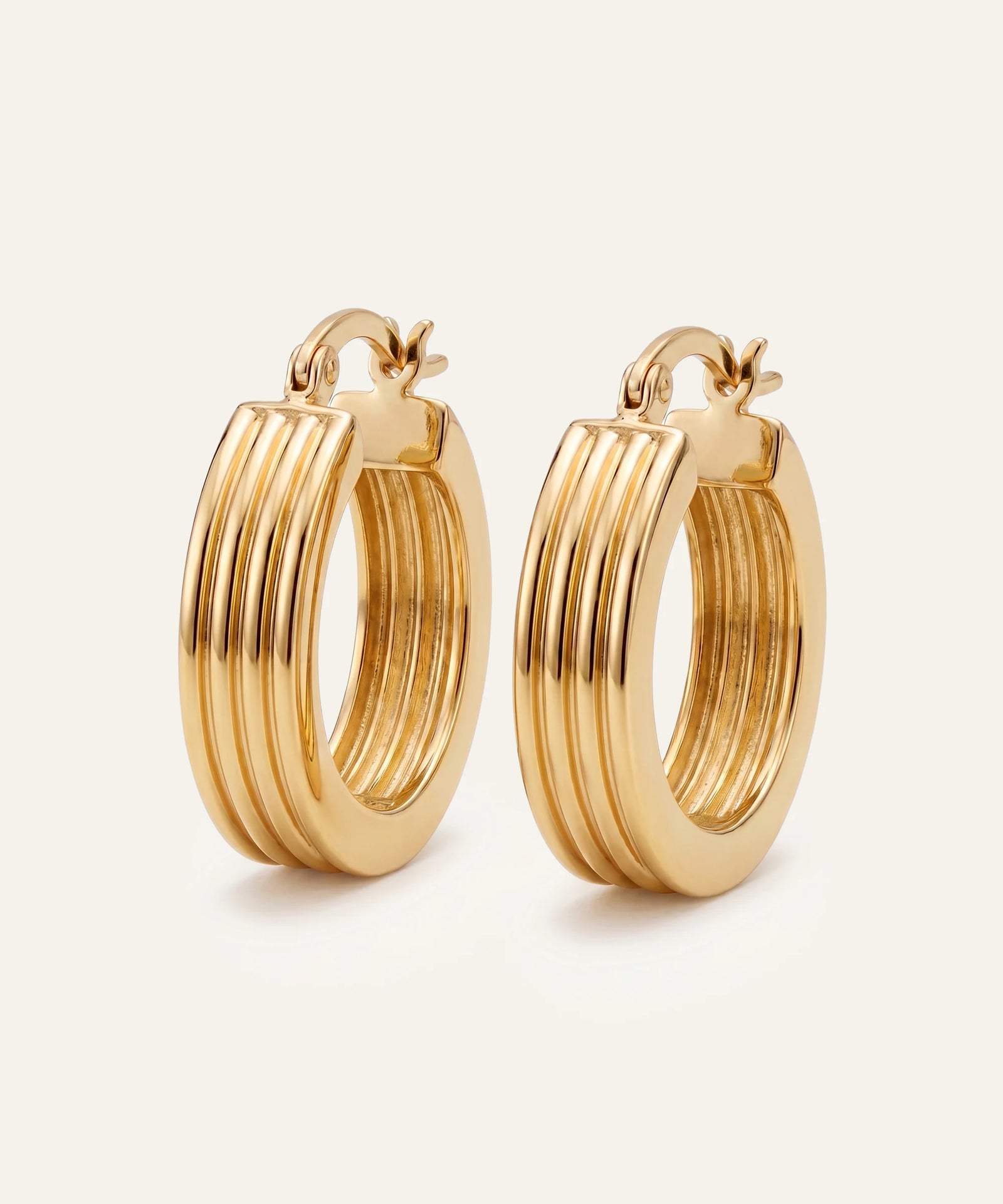 Gold hoop earrings on a light beige background