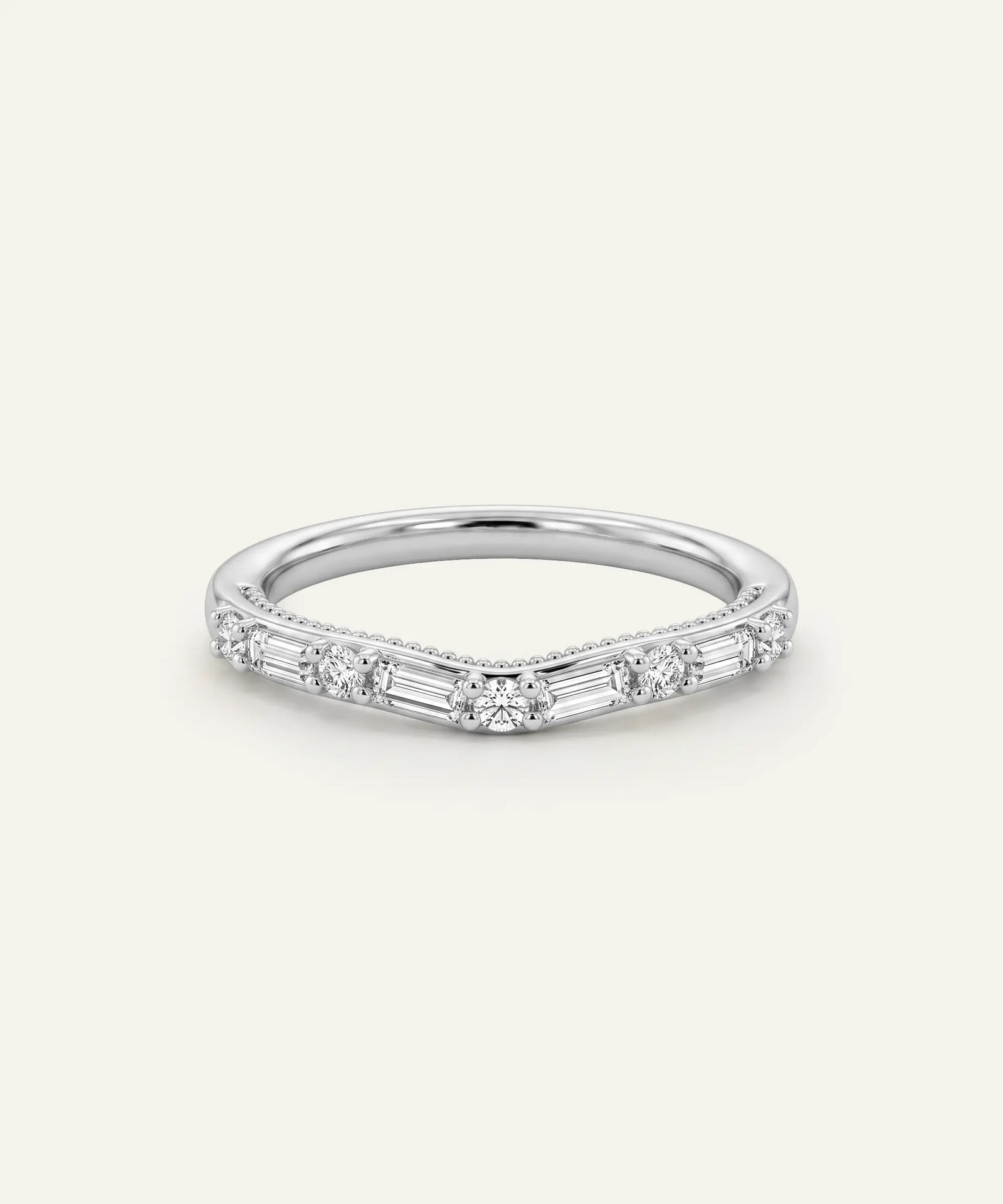 A silver V-shaped band ring featuring baguette and round-cut diamonds, set against a solid off-white background.