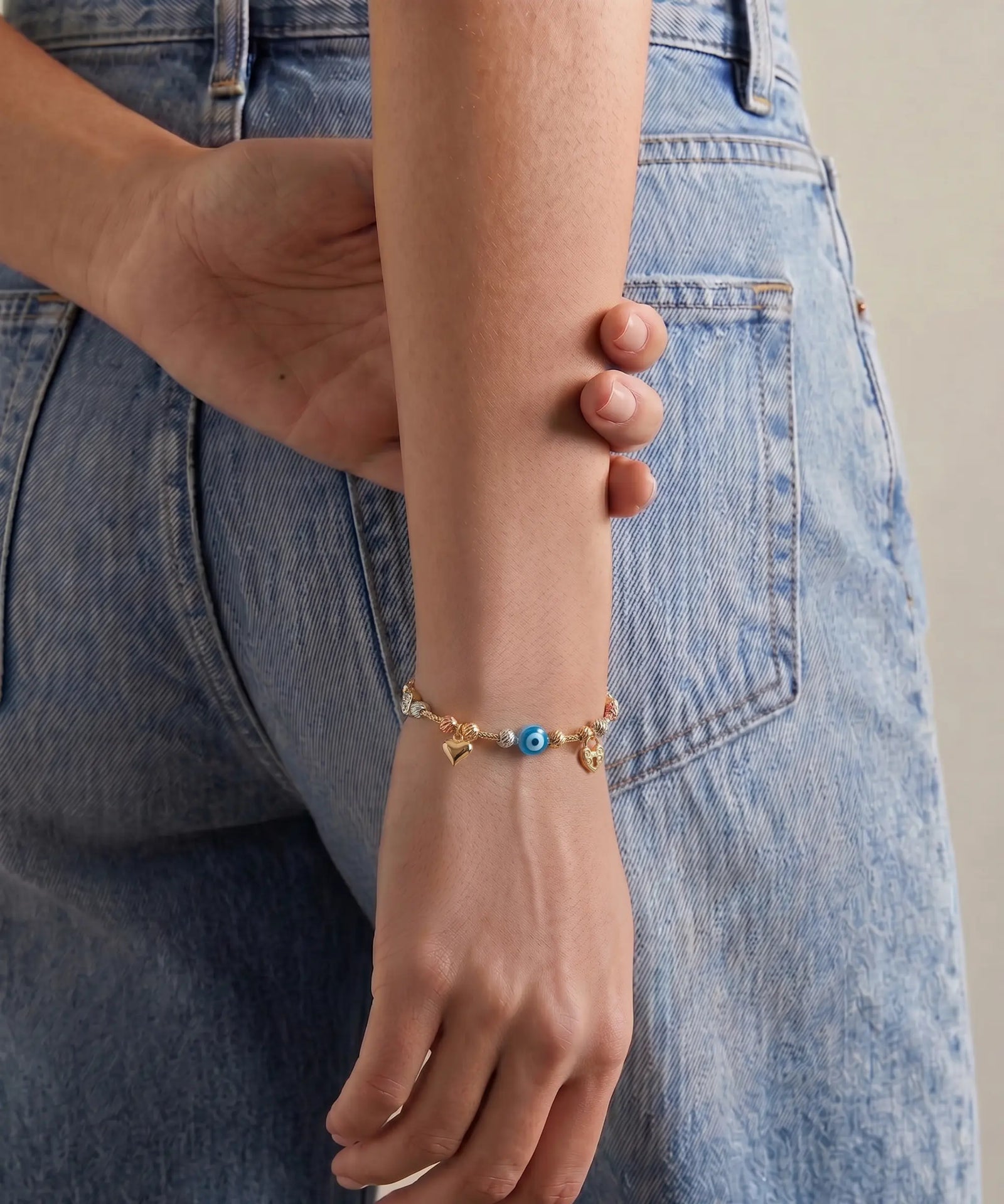 Person wearing a bracelet with colorful beads against a denim background