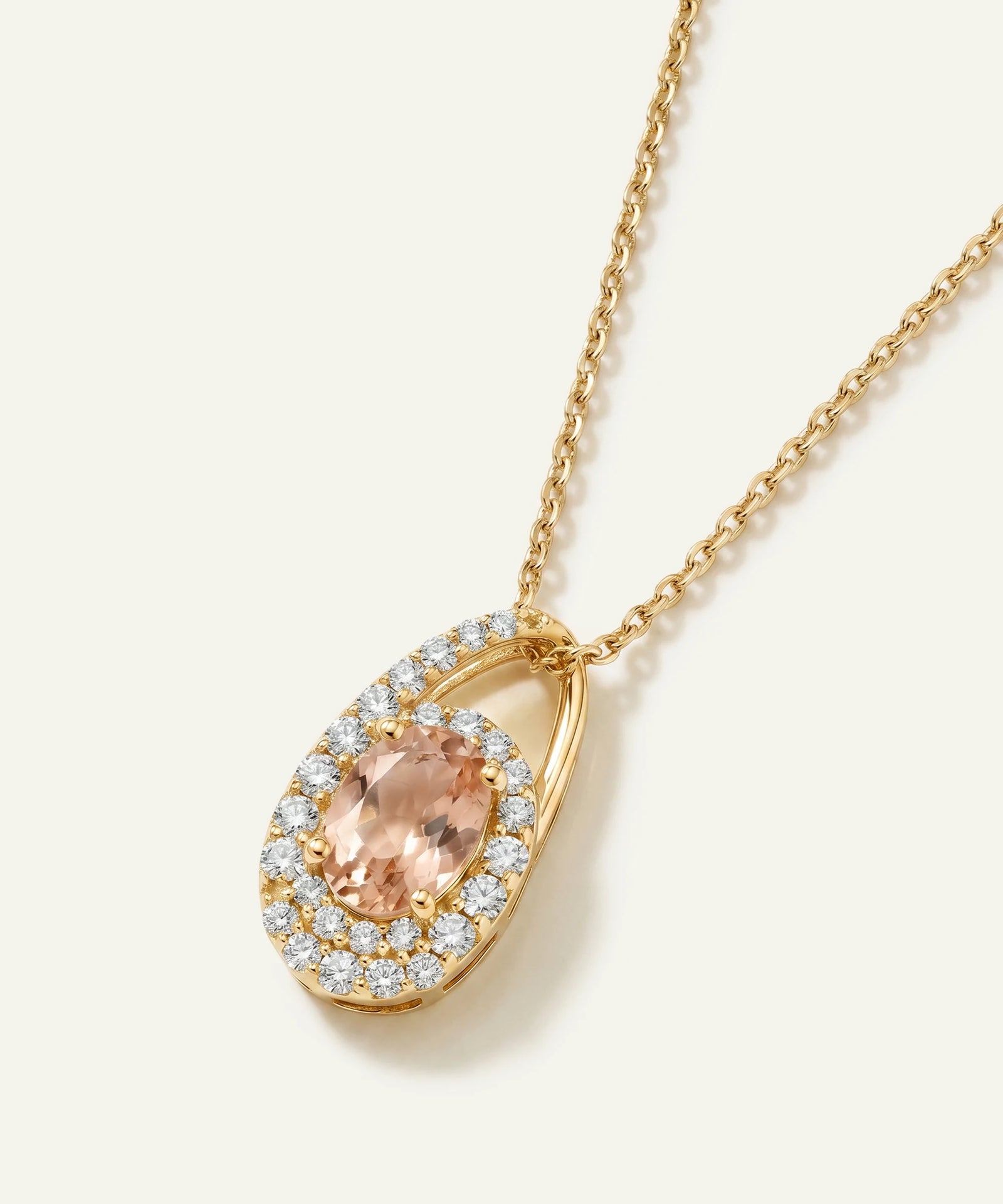 Gold necklace with a peach-colored gemstone and diamond accents on a white background