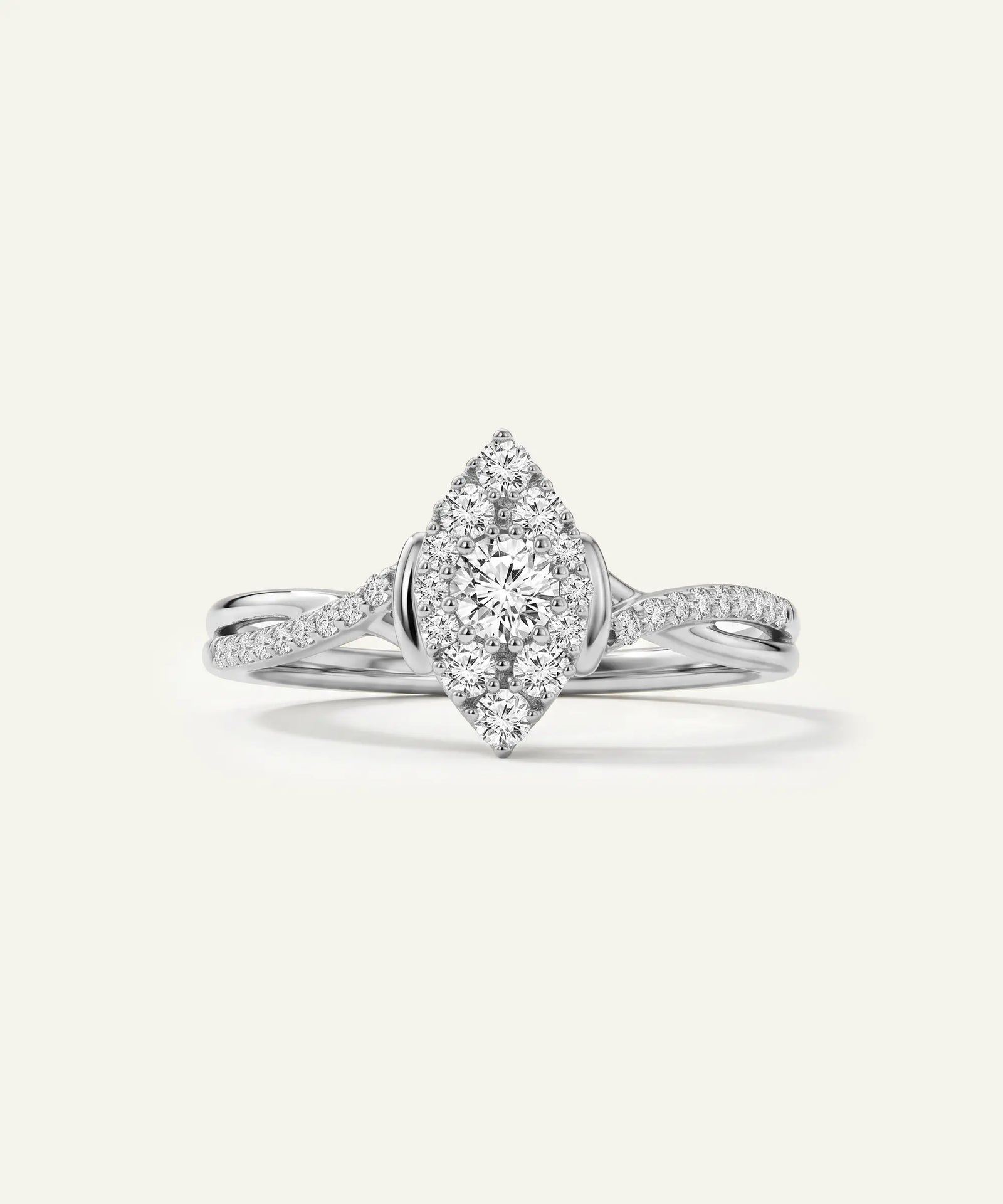 A silver-tone diamond ring with a marquise-shaped halo center stone and pavé-set band, shown on a light cream background.