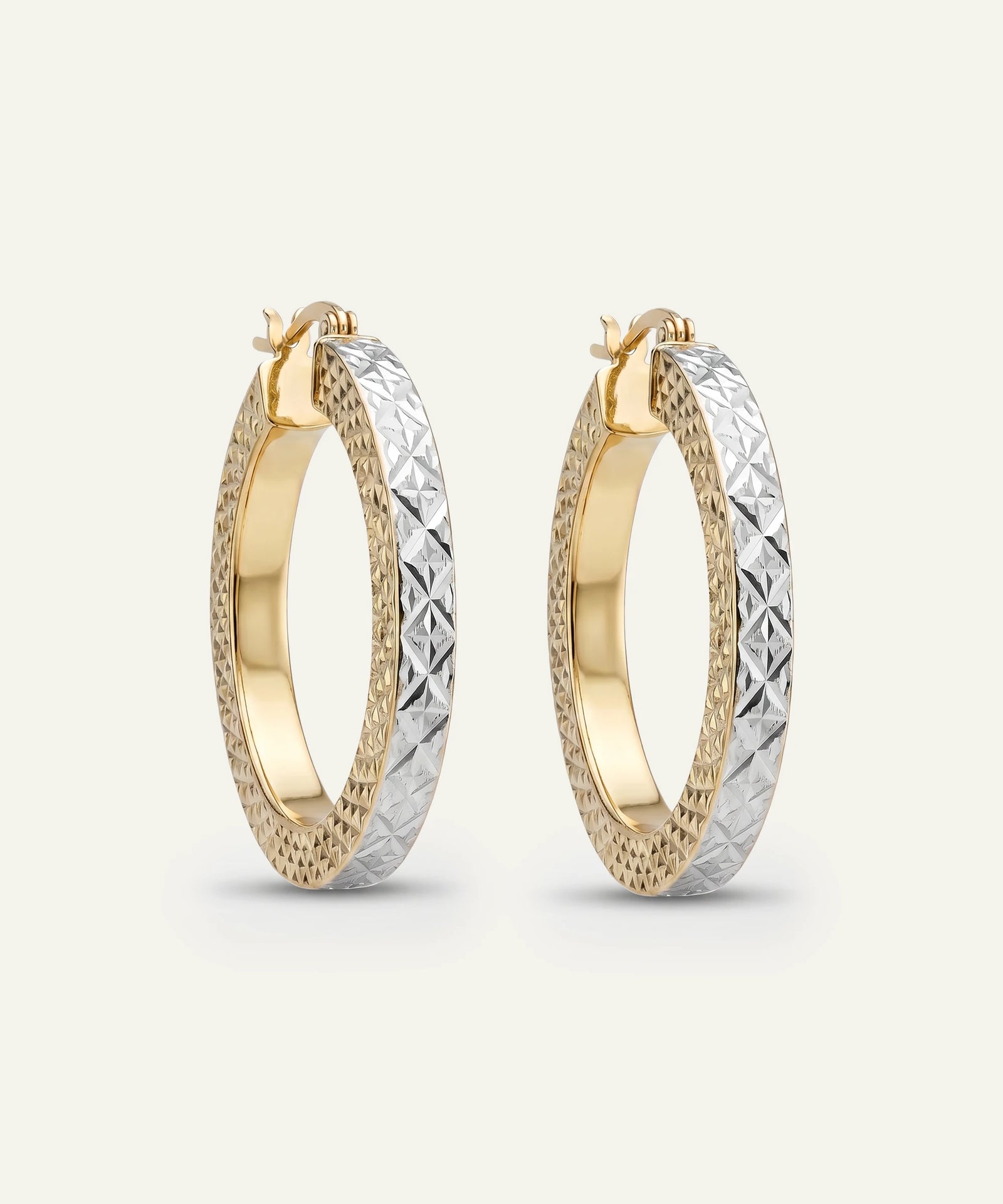 Two-tone gold hoop earrings on a light gray background