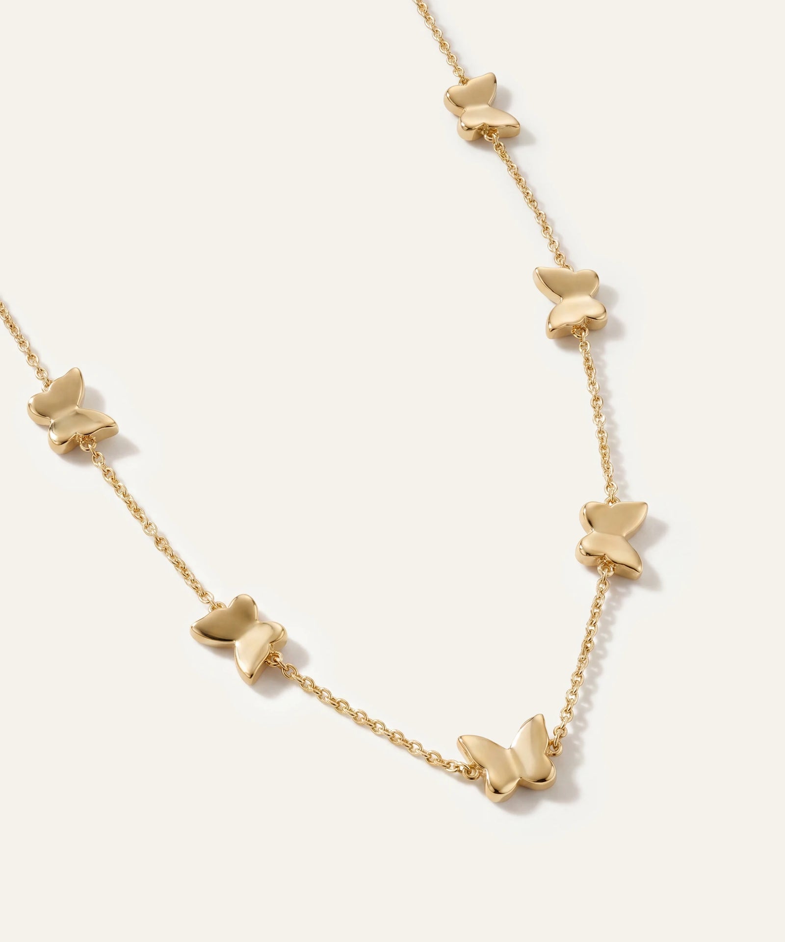 Gold butterfly necklace on a white background