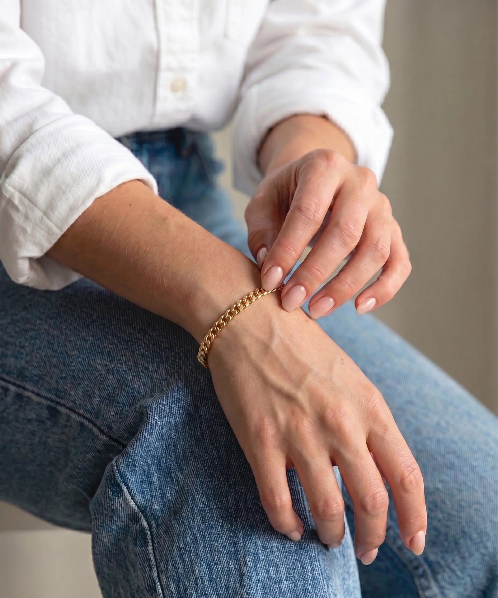 Person wearing a gold bracelet on a blurred background