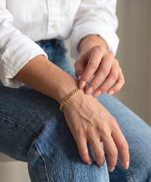 Person wearing a gold bracelet on a blurred background