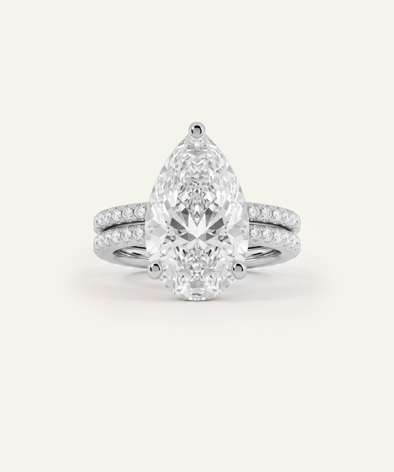 A pear-cut diamond engagement ring with a matching pear-shaped center stone and a slim pavé band, shown on a clean off-white background.