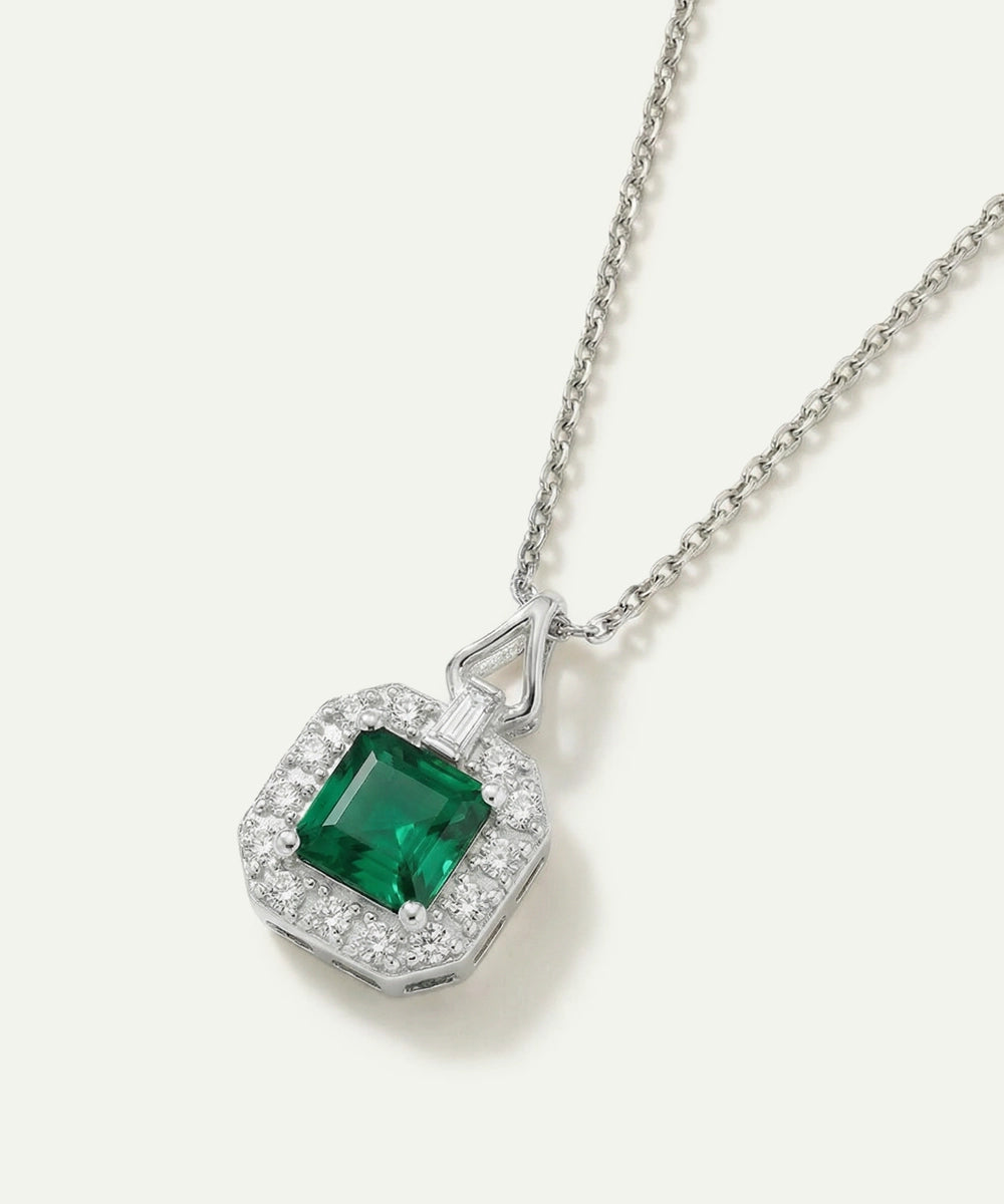 Silver necklace with a green gemstone pendant on a white background