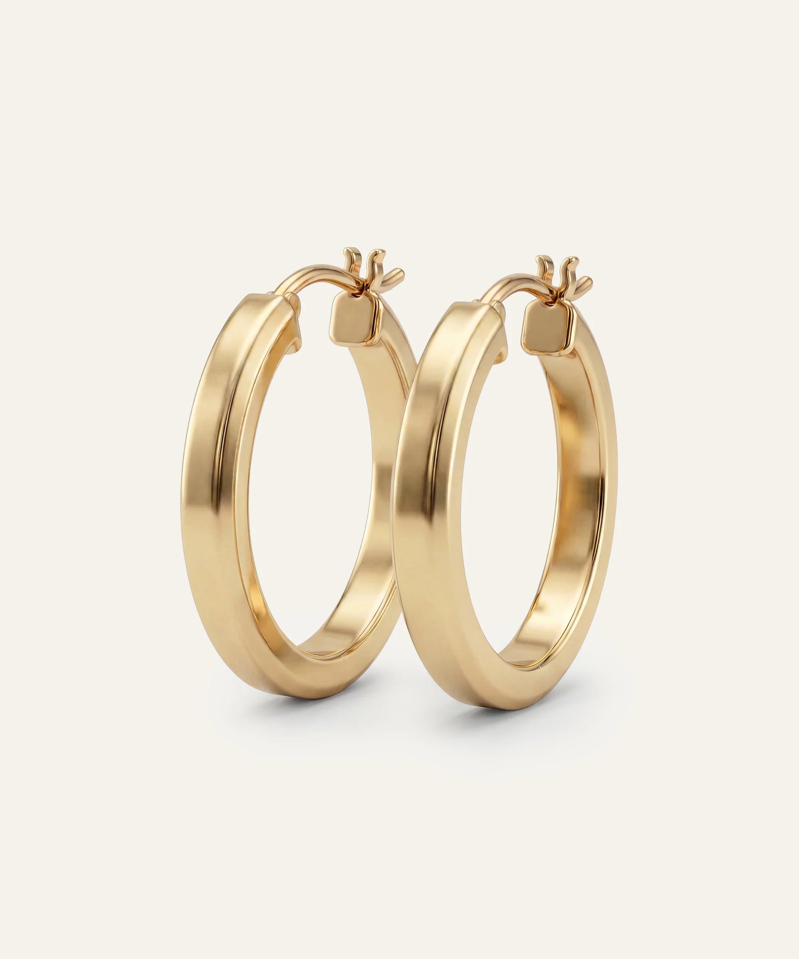 Gold hoop earrings on a light beige background