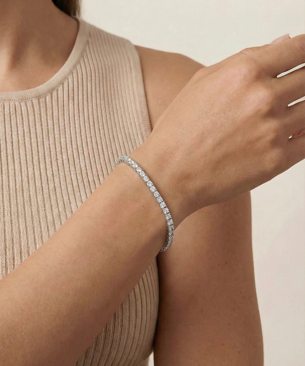 Close-up of a person wearing a diamond bracelet on a neutral background