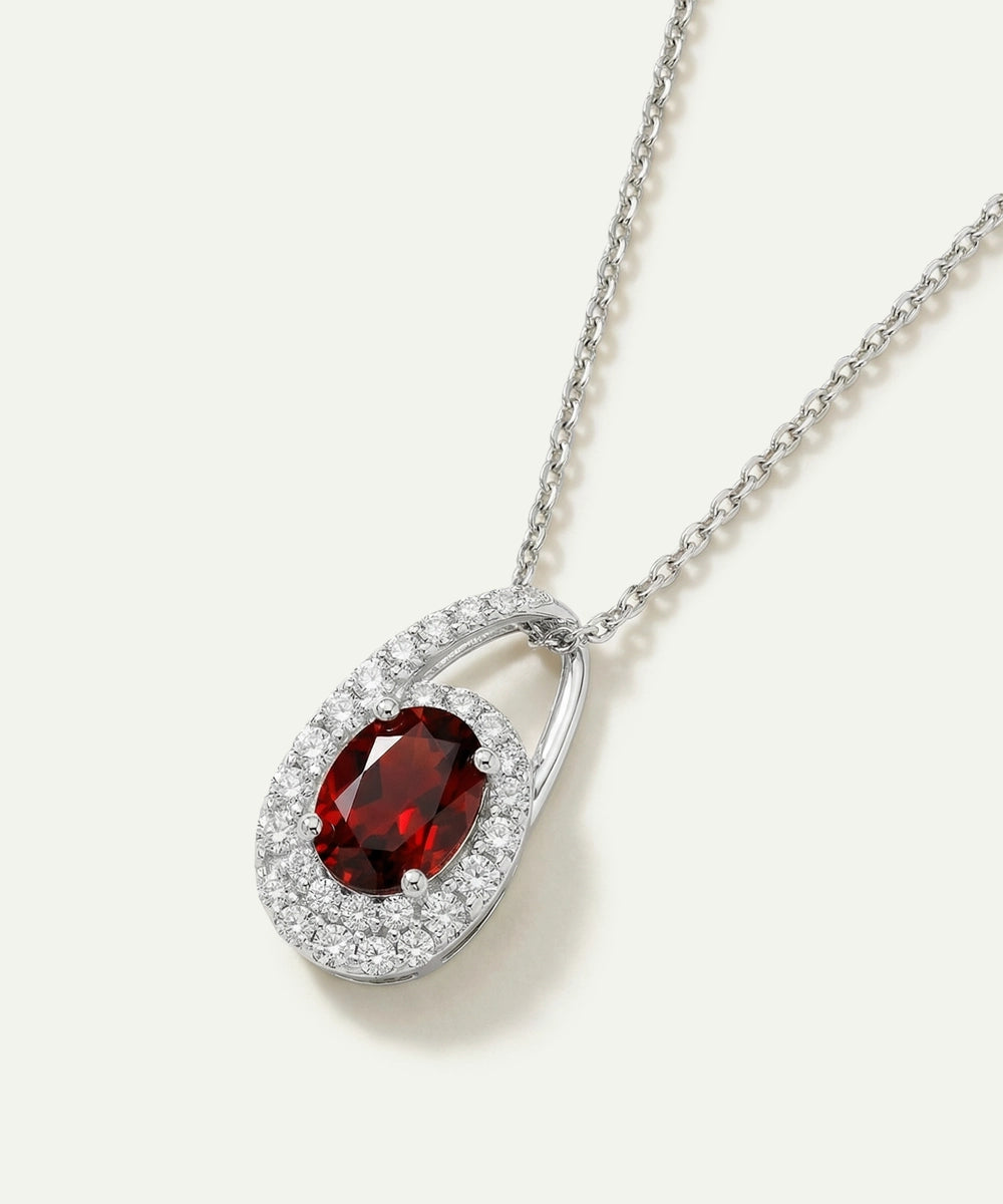 Silver necklace with a red gemstone pendant on a white background