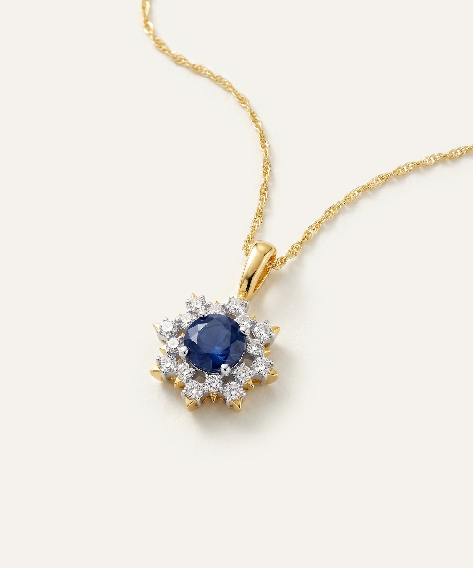 Gold necklace with a blue gemstone and diamond accents on a white background