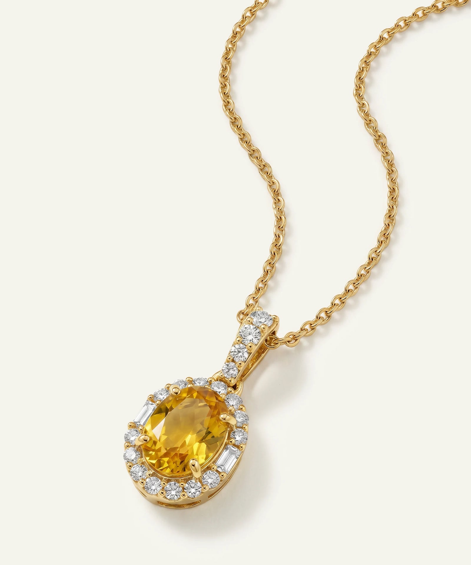 Gold necklace with a yellow gemstone pendant on a white background