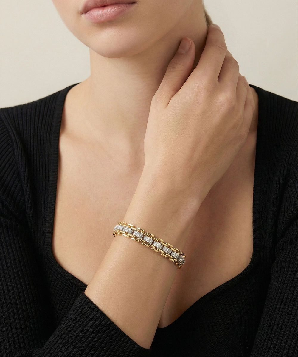 Gold bracelet with clear stones on a wrist against a neutral background